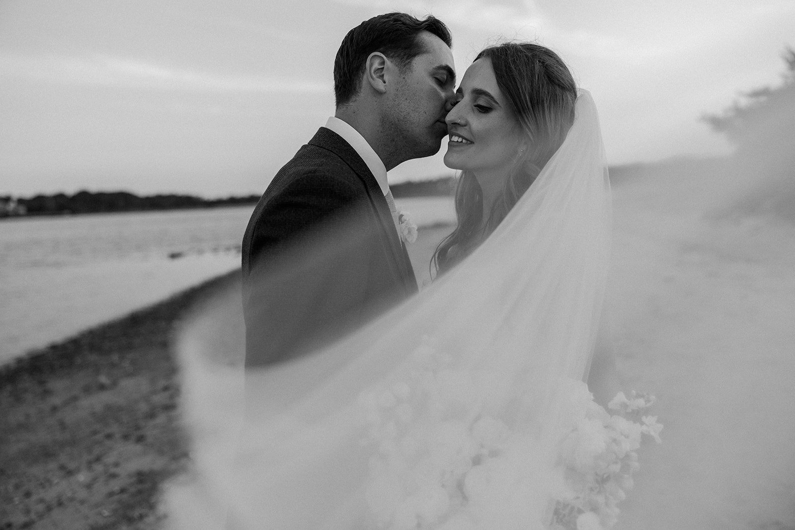 A bride and groom kissing in a black and white wedding photo