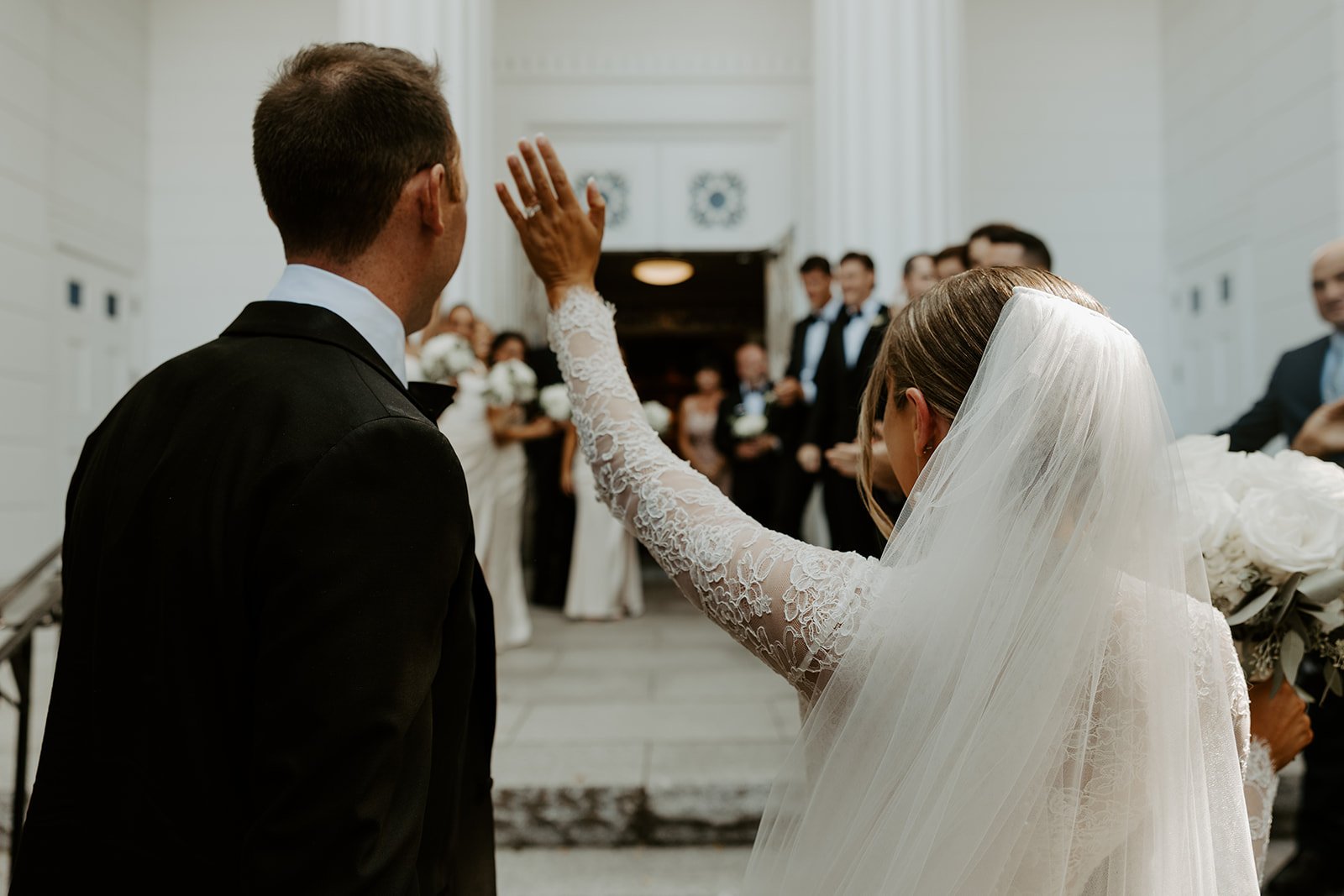 A bride and groom waving to their wedding guests