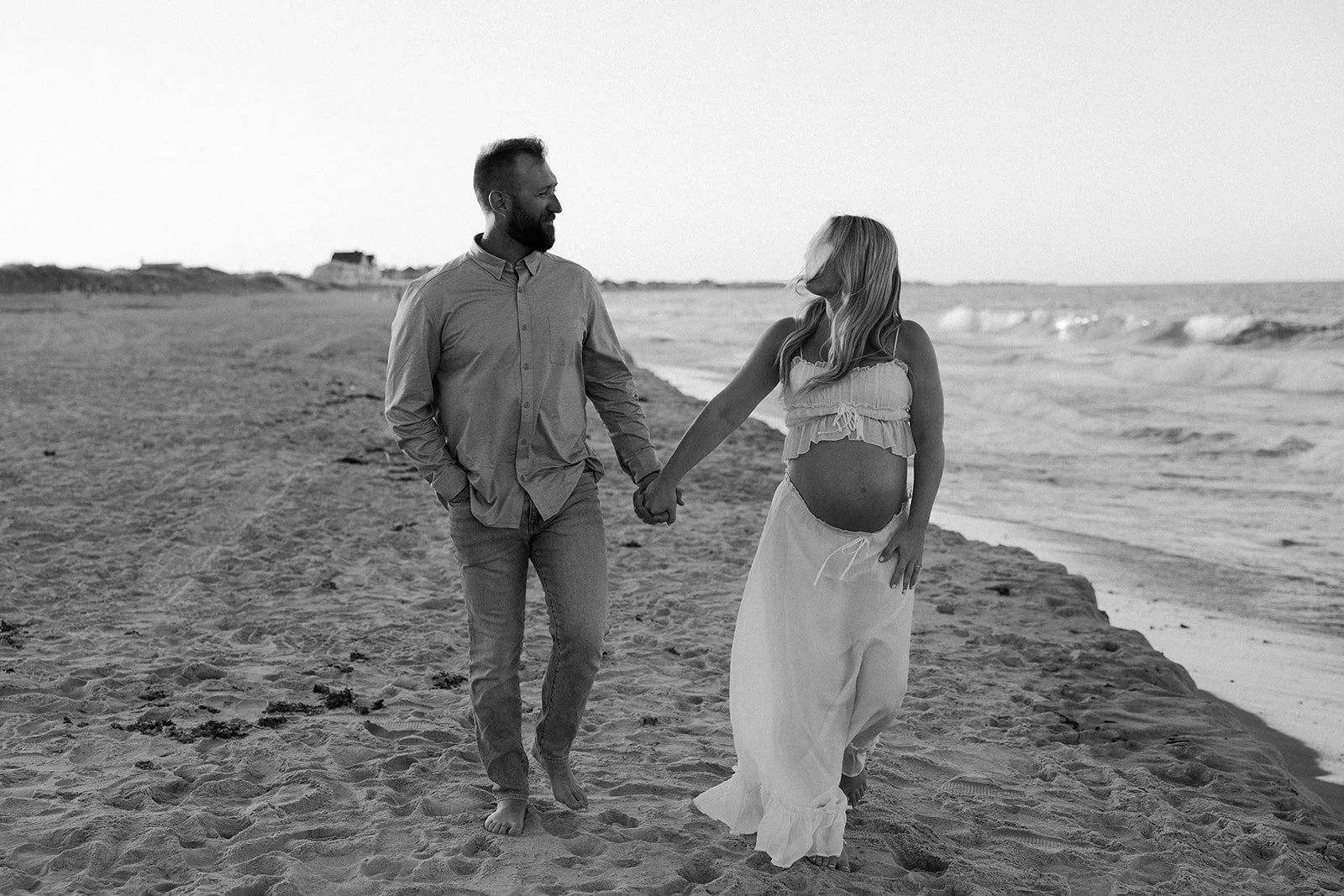 A couple holding hands for beach maternity photos