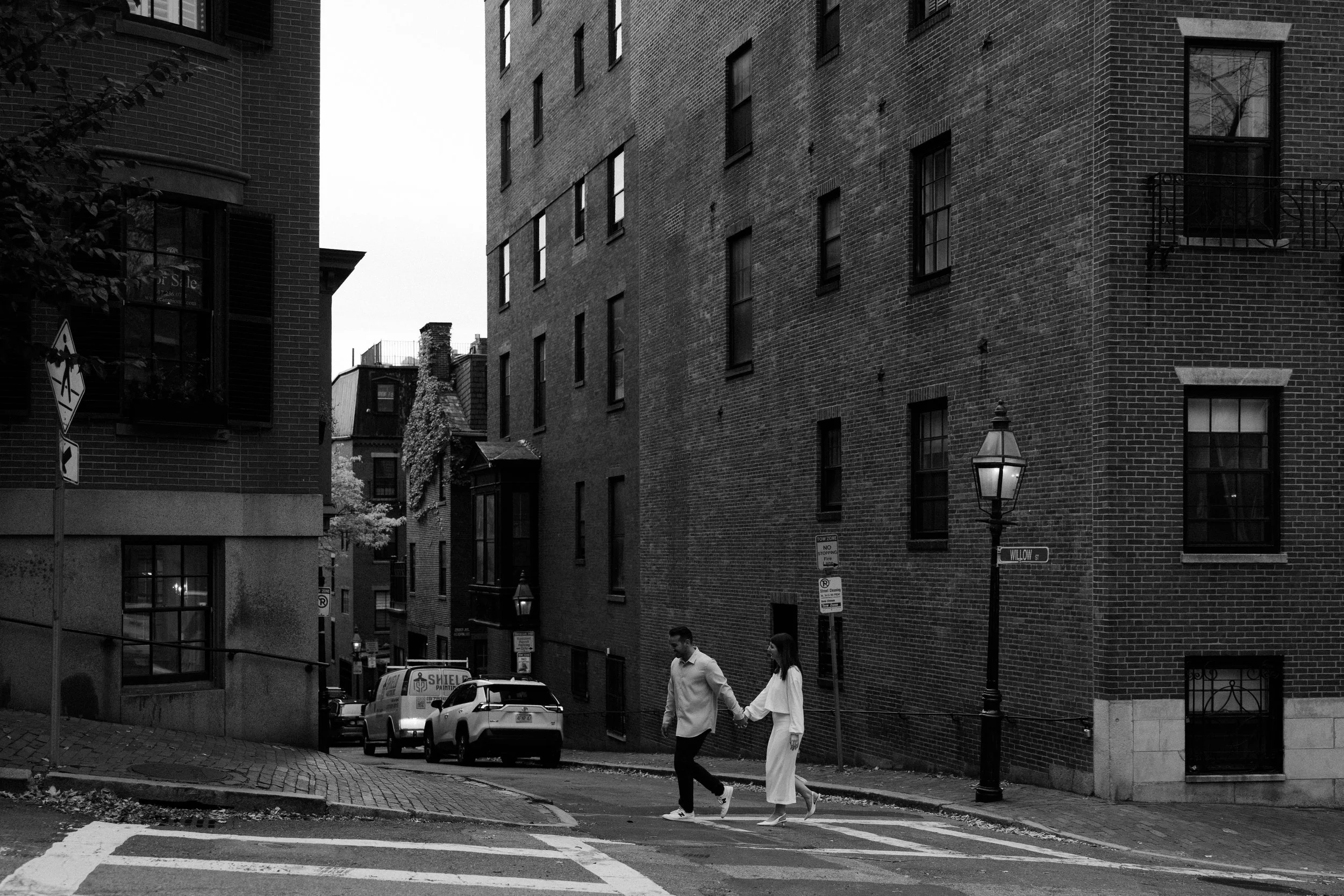 A black and white photo of a couple crossing the street at Beacon Hill, captured by a Boston Engagement photographer