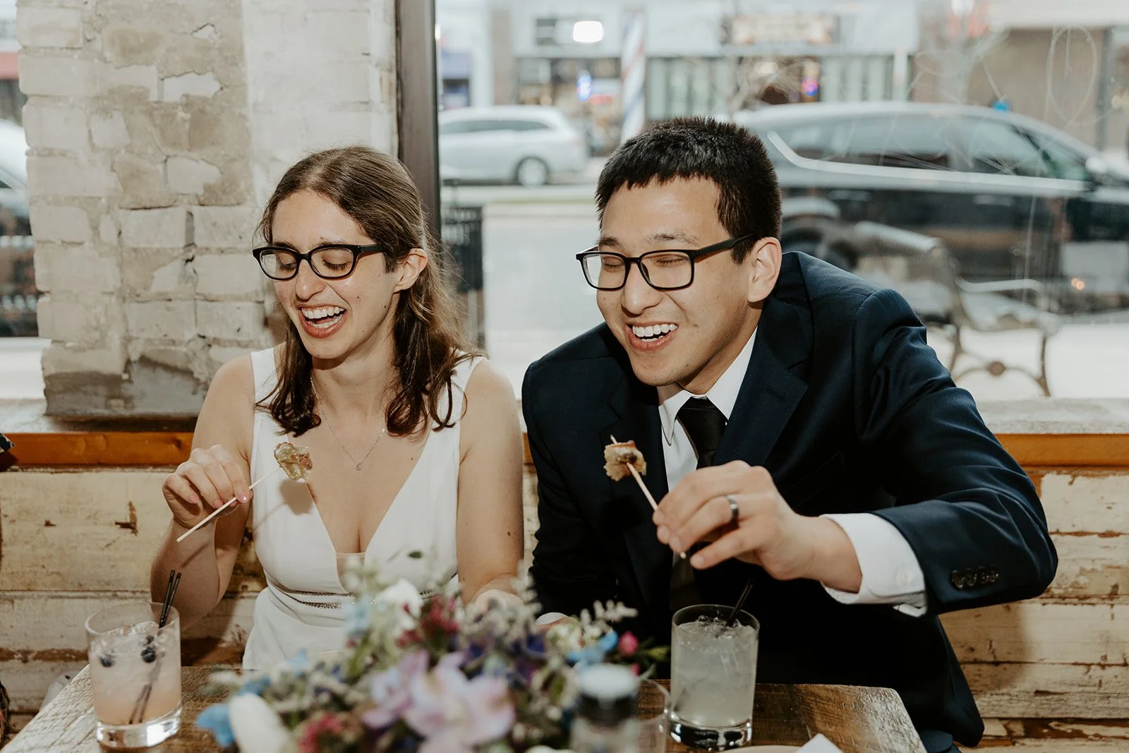 A candid photo of a bride and groom laughing at their restaurant wedding reception
