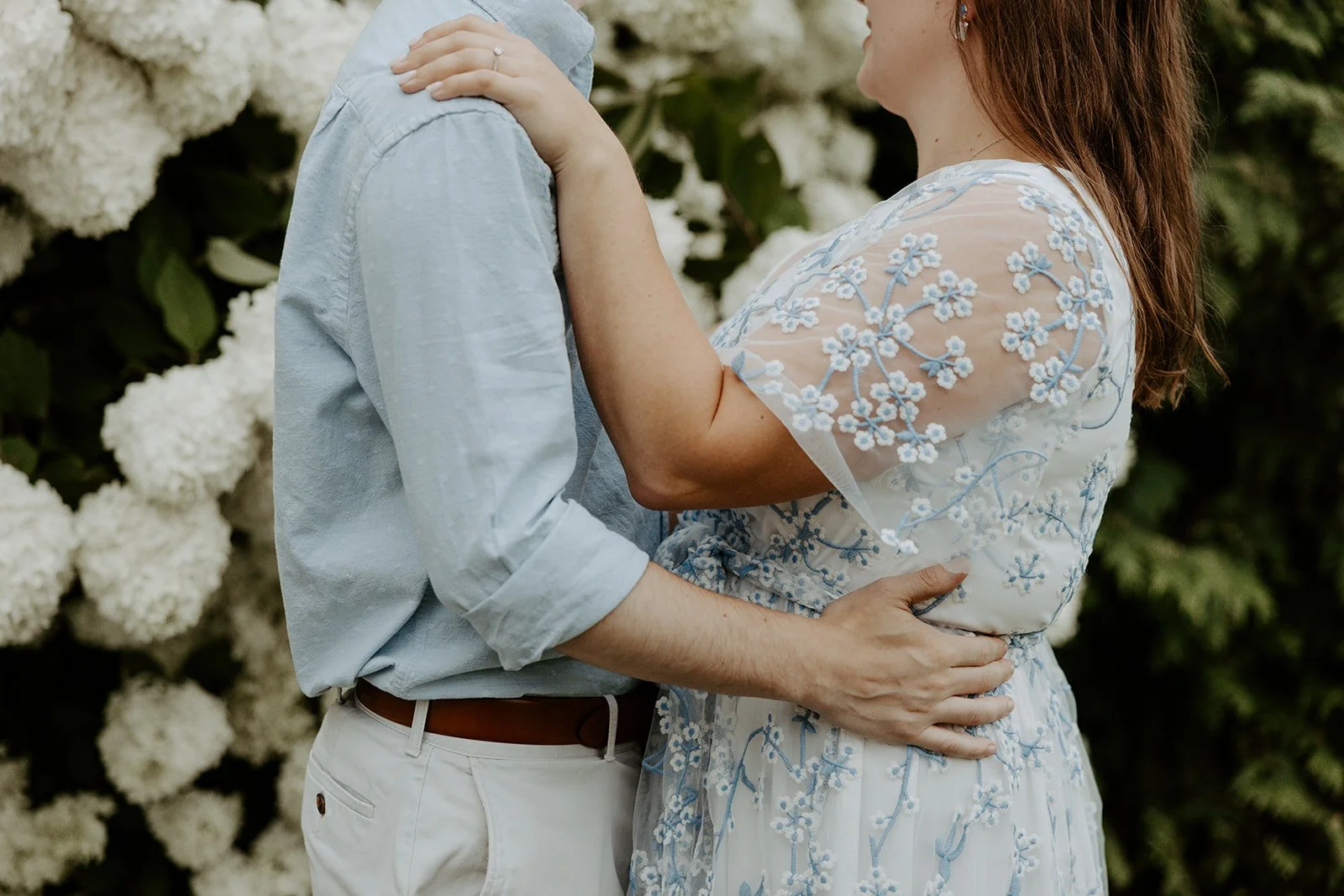 A couple posing in front of flowers at their Massachusetts engagement photo location
