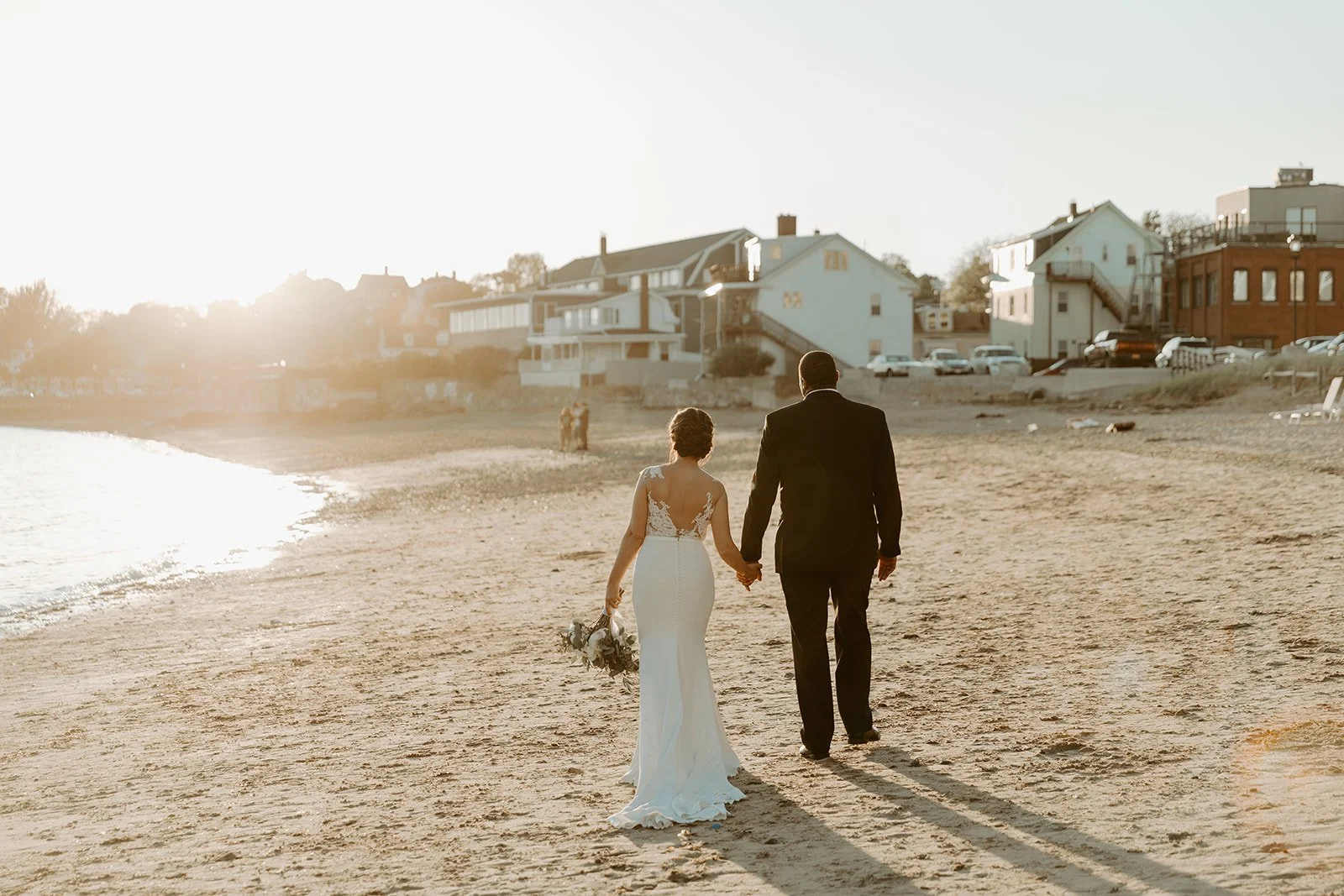 A bride and groom walking on the beach during sunset photos