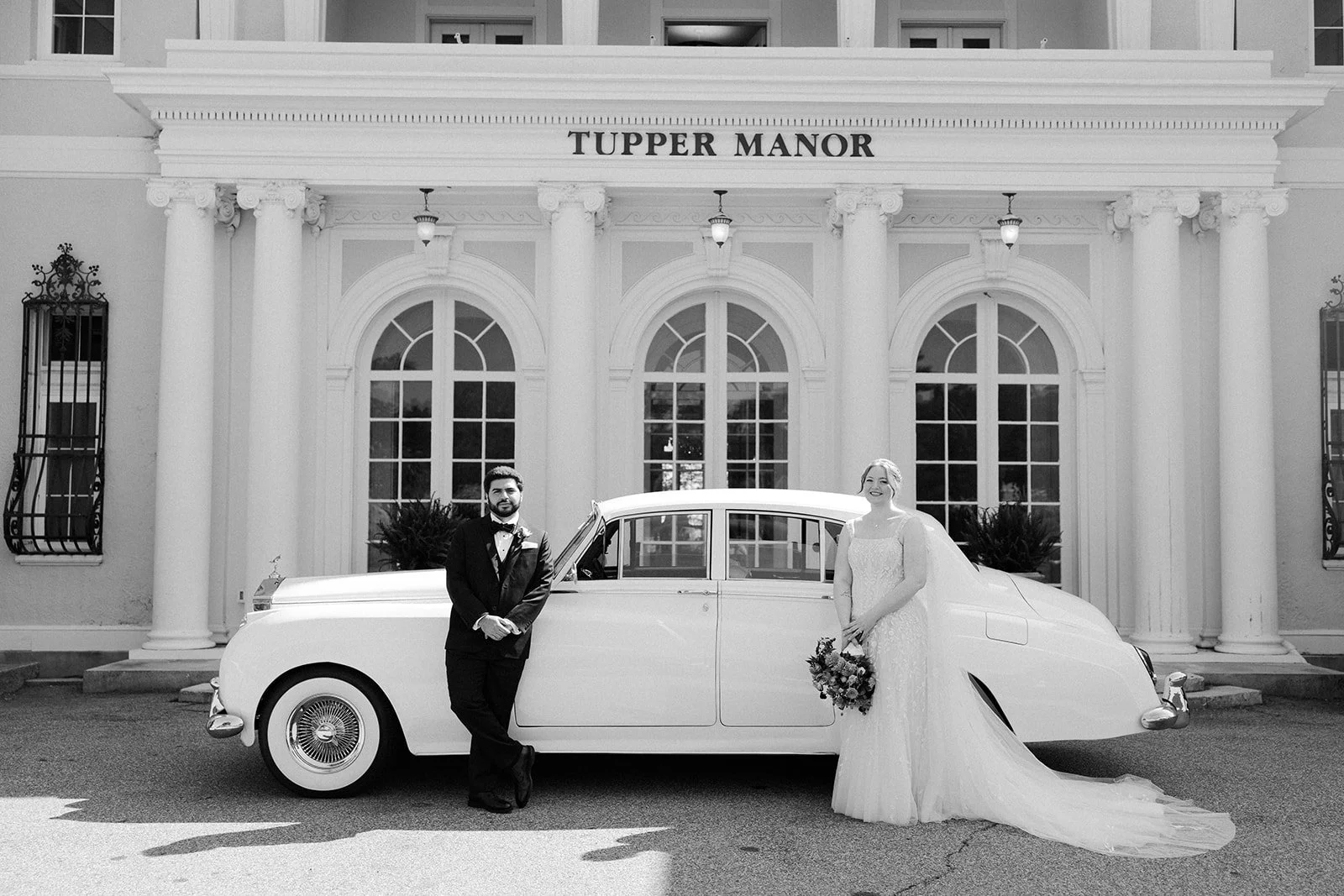 A black and white photo of a couple in front of Tupper Manor