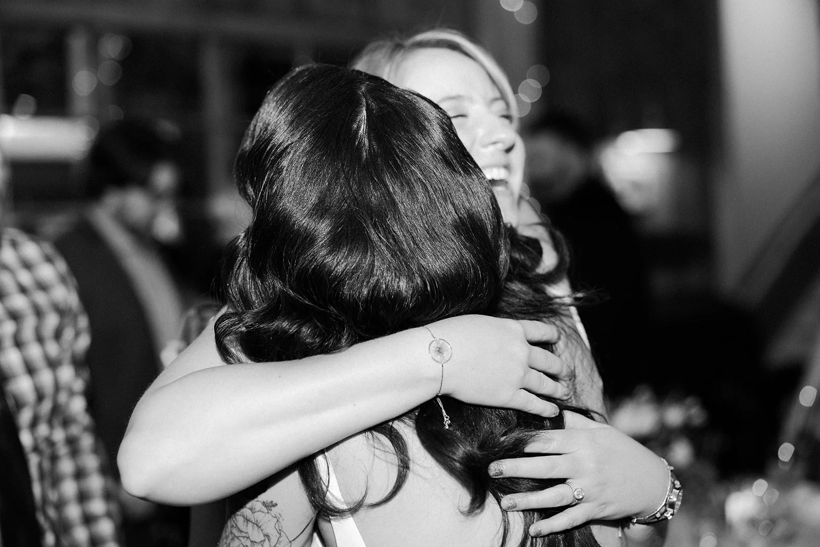 A bride hugging a friend in a candid wedding photo