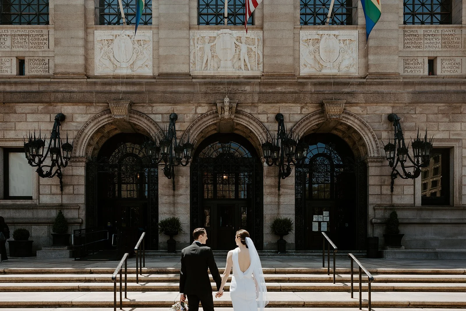 A bride and groom walking into their boston public library wedding