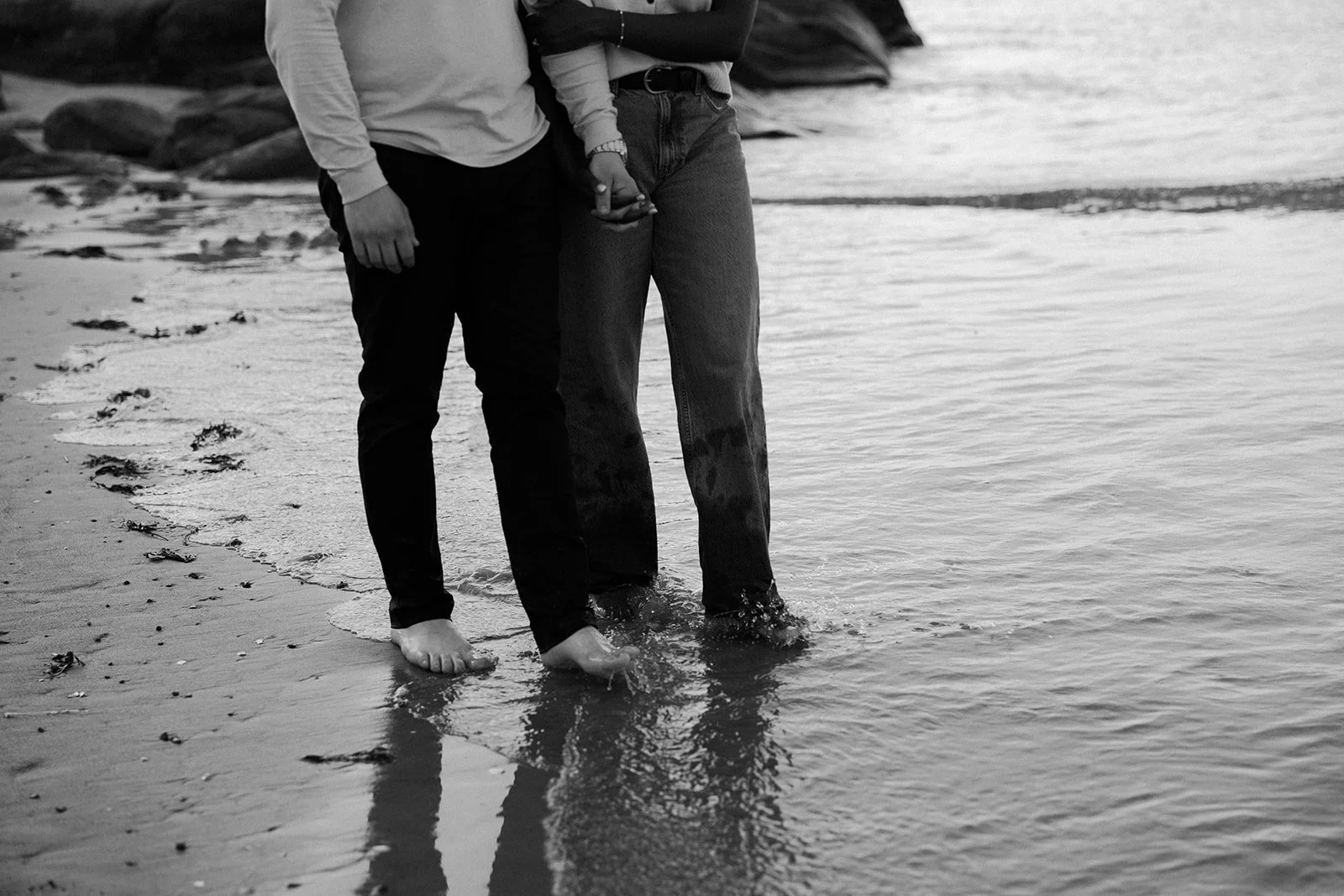 An up close photo of a couple walking through the water during their beach engagement photoshoot
