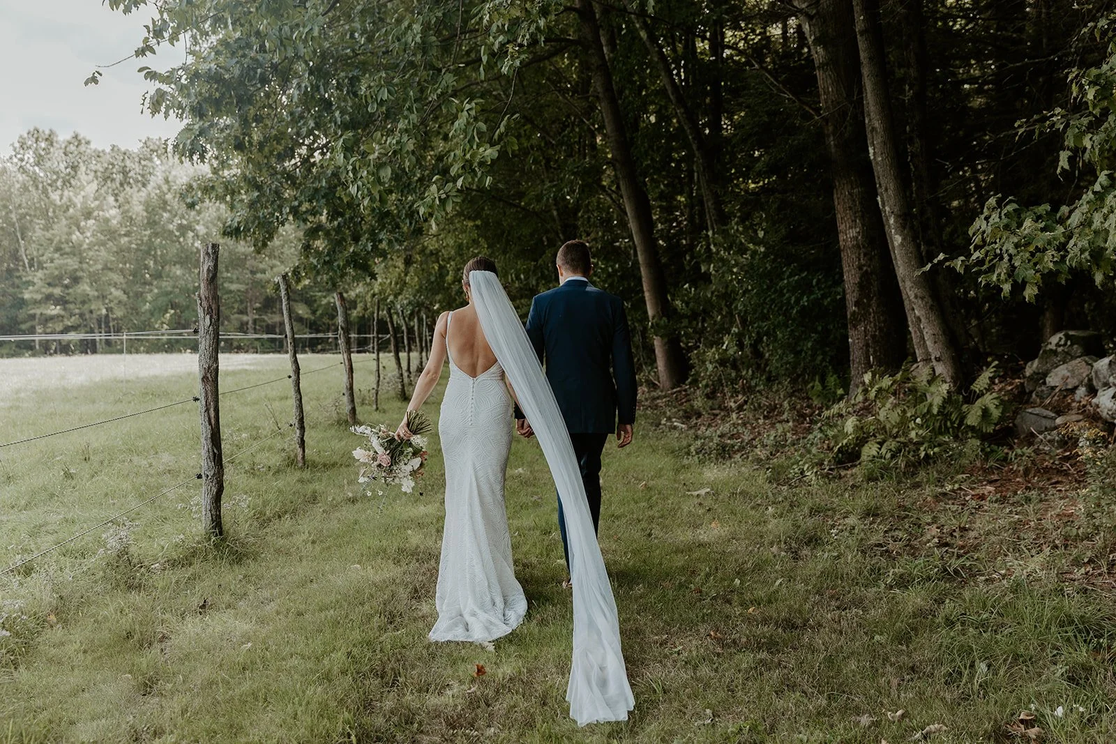 A bride and groom walking through the orchards at valley view farm