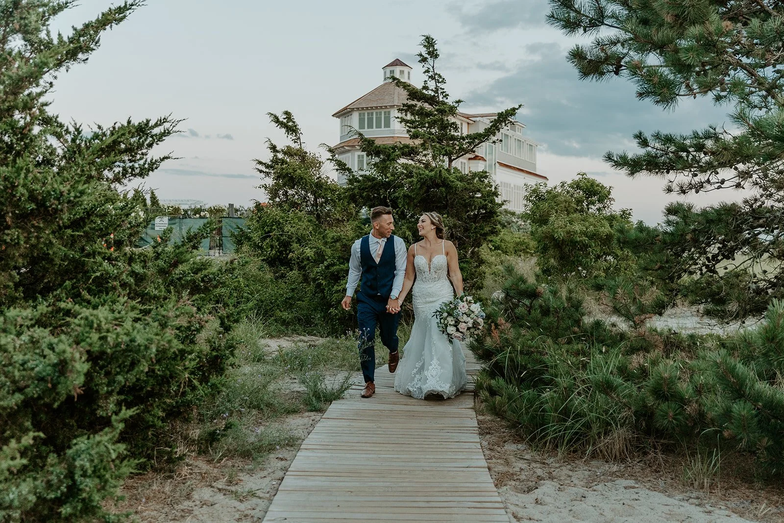A bride and groom walking hand in hand at their cape cod wedding venue