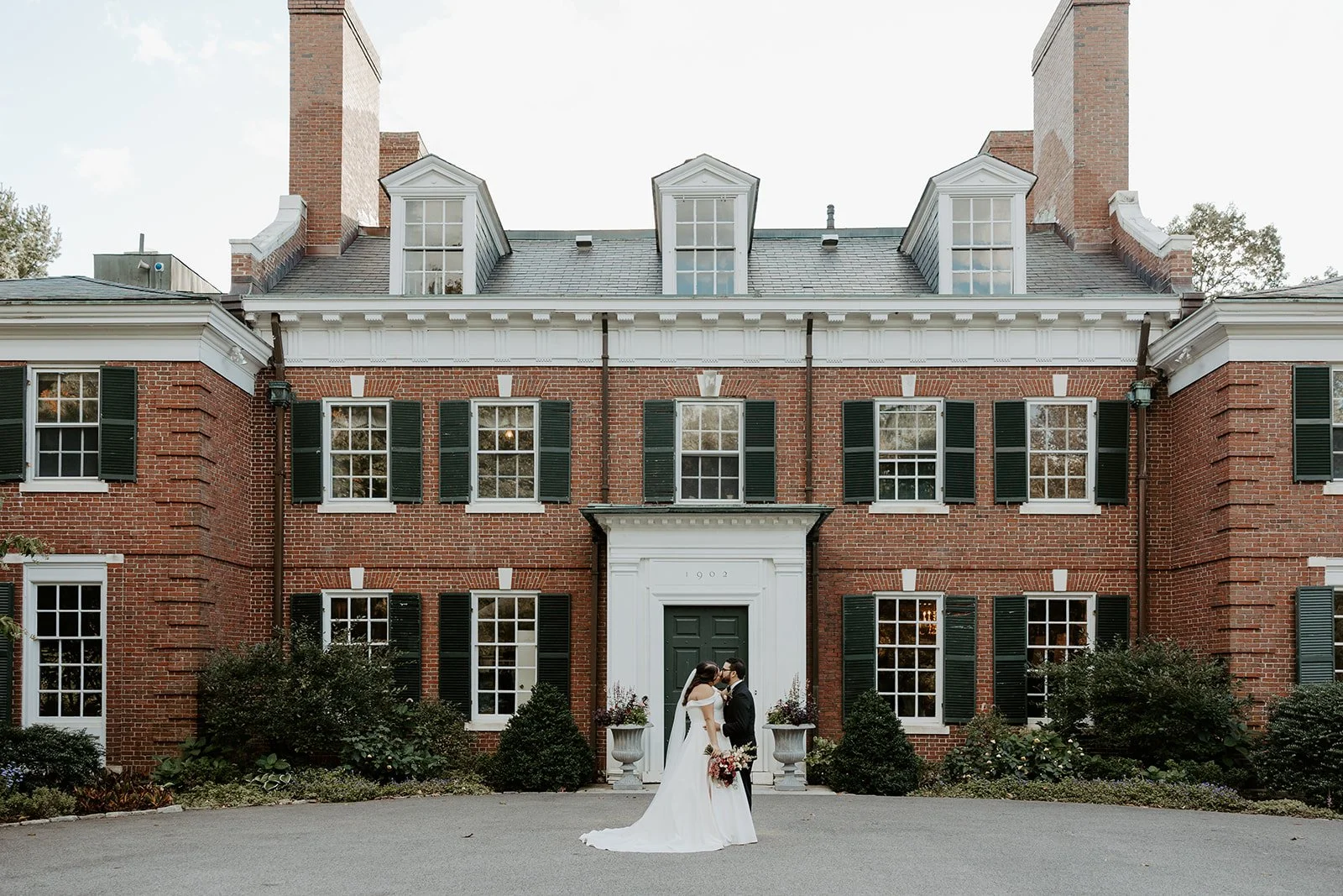 A bride and groom in front of an estate wedding venue
