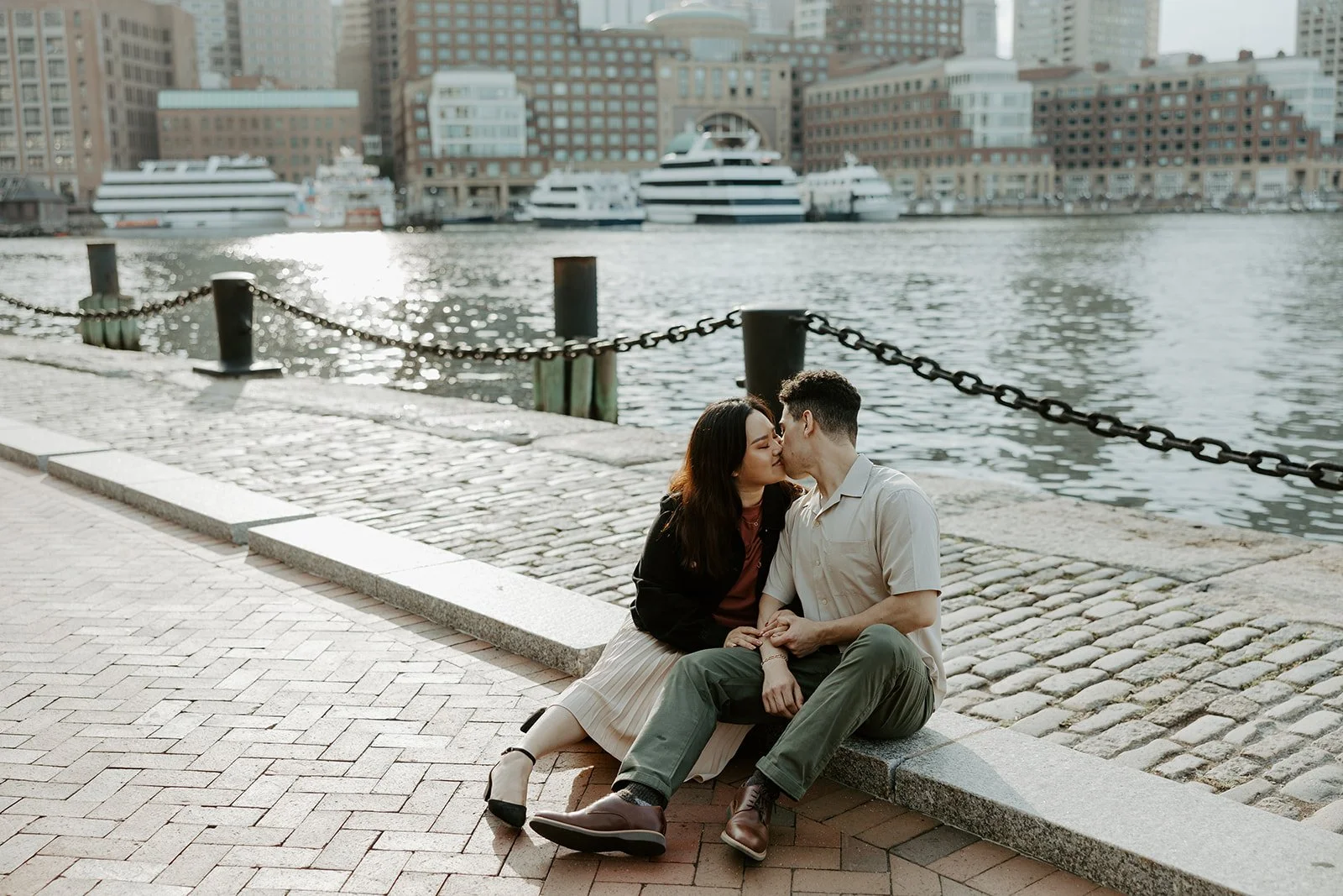 A couple sitting on the ground in front of the water at Fan Pier Park