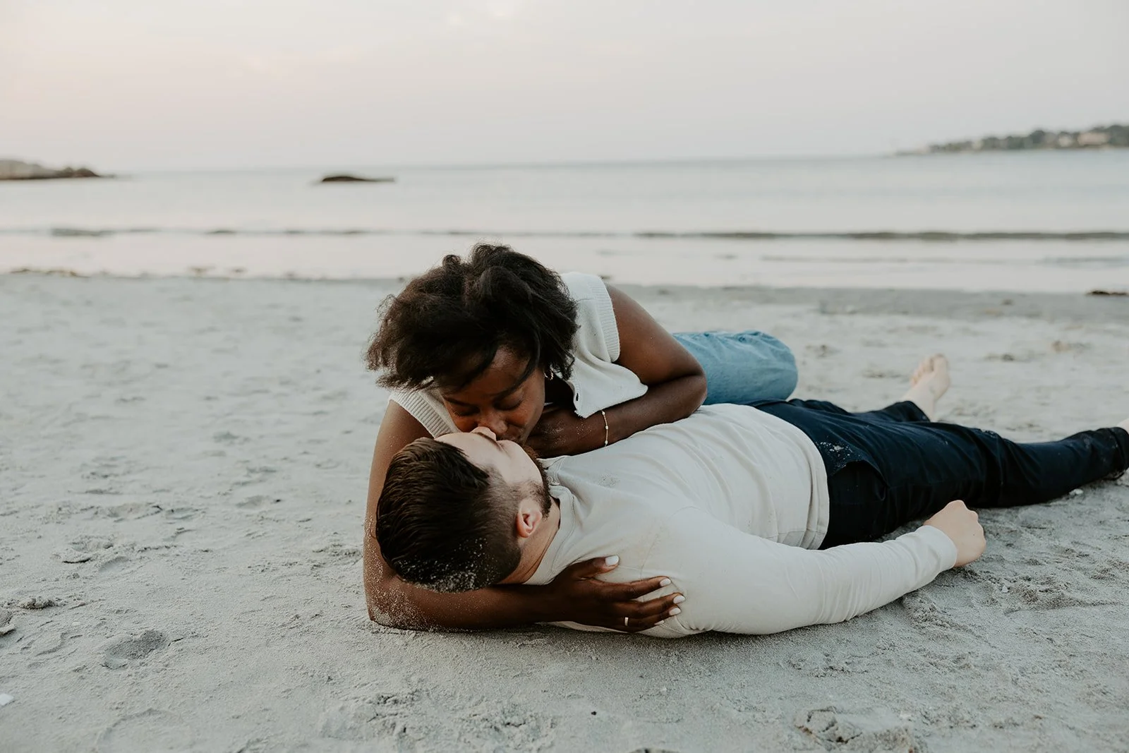 A couple laying in hte sand on Wingaersheek beach