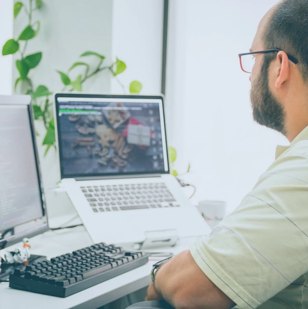 Male Custom Software Developer Working on Laptop and Desktop