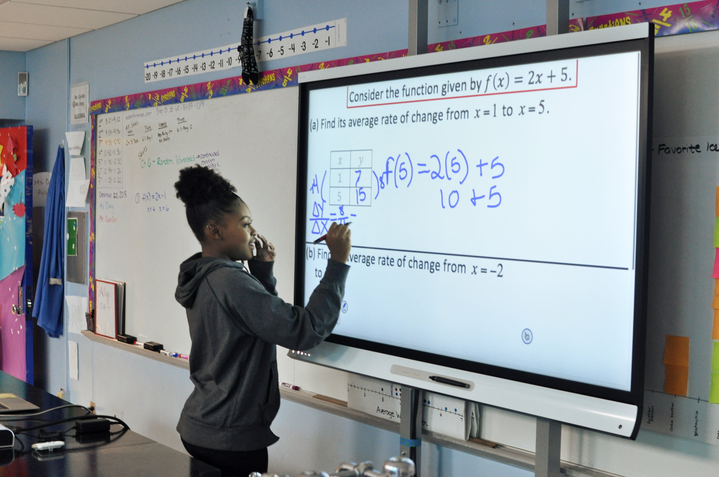 student works on math problem on smart board