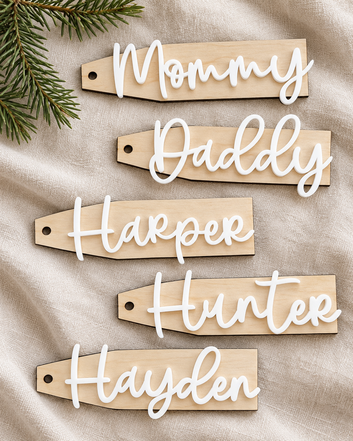 Five birch wood stocking tags with raised white acrylic names on neutral linen