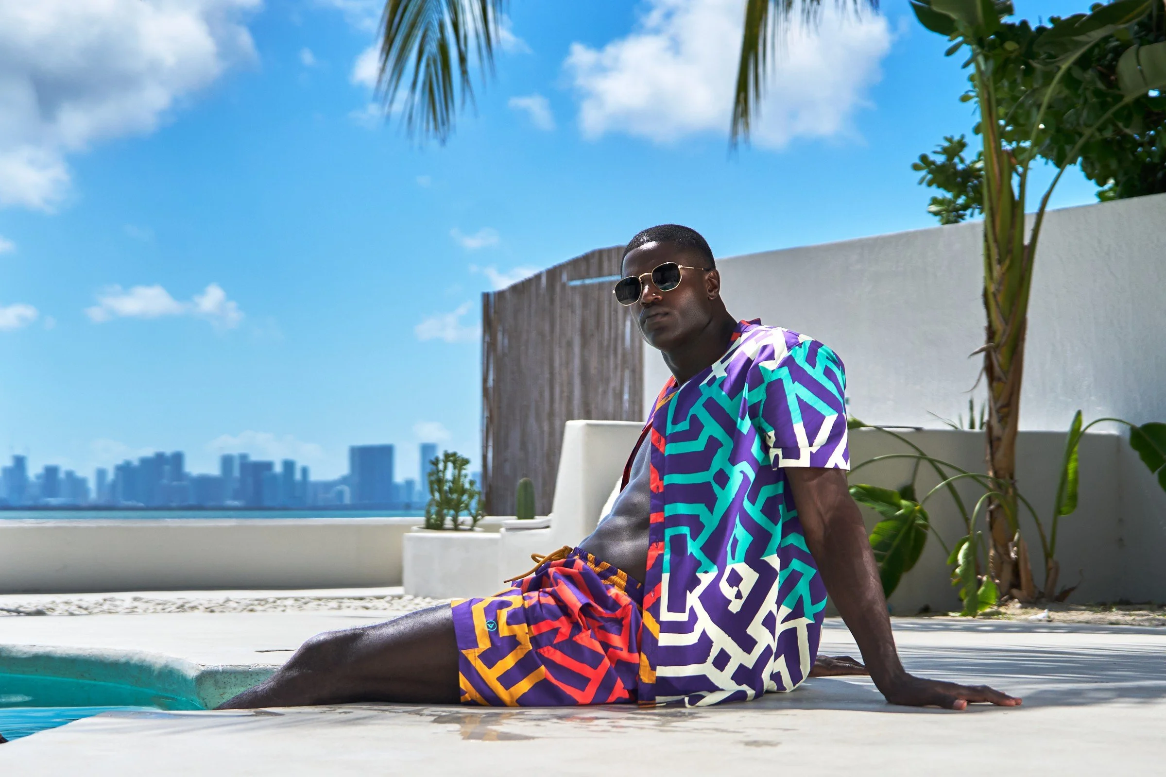 Men’s African-inspired swimwear beside a waterfront pool