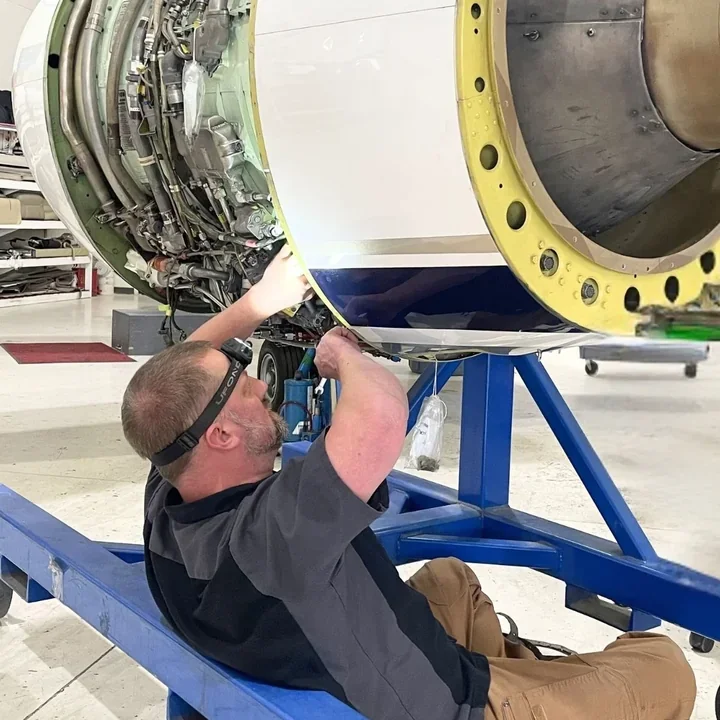 Technician working beneath a Cessna Citation engine