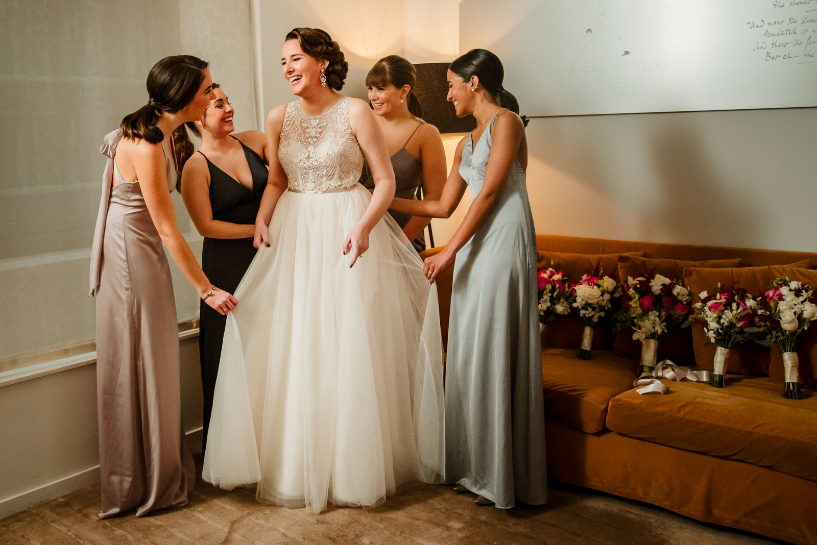 Bridesmaids help bride with her dress