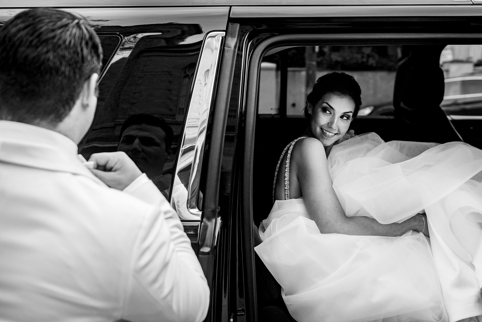 Bride looks at groom  in car