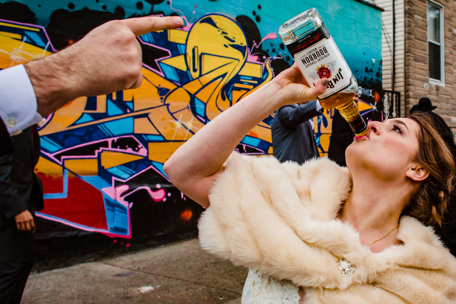 Bride drinks hard liquor from bottle outdoors