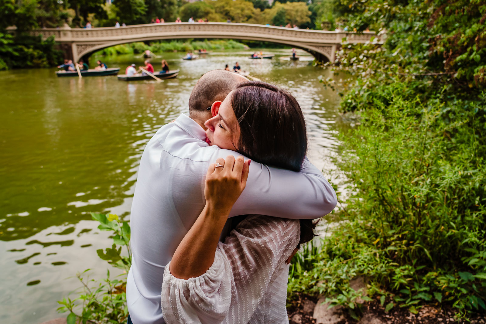 Couple hugs after proposal near Bow Bridge in Central Park