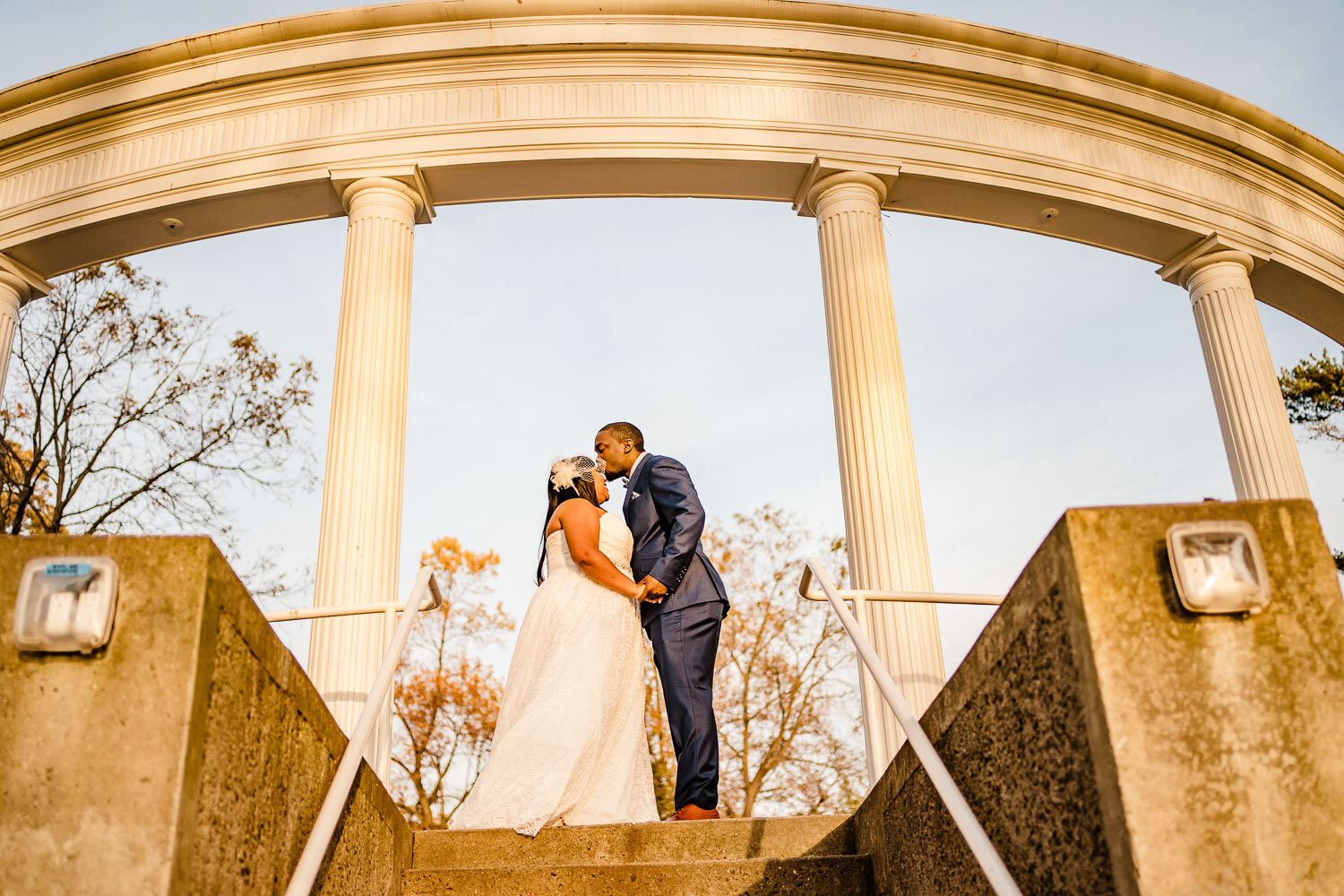 Groom kisses bride under arches in Morgan Memorial Park in Glen Cove 