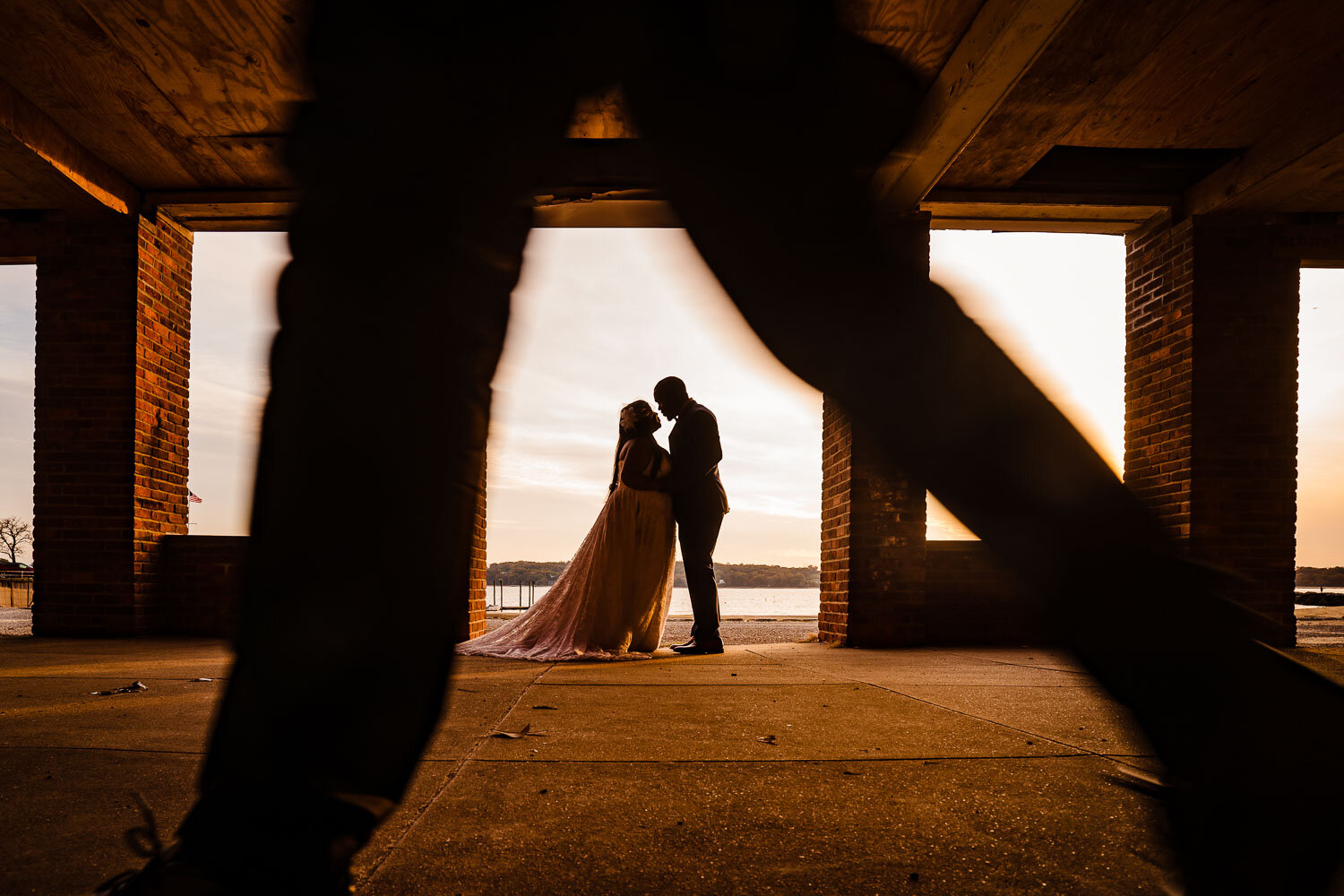 Bride and groom portrait while somebody passes by in forground in Morgan Memorial Park in Glen Cove 