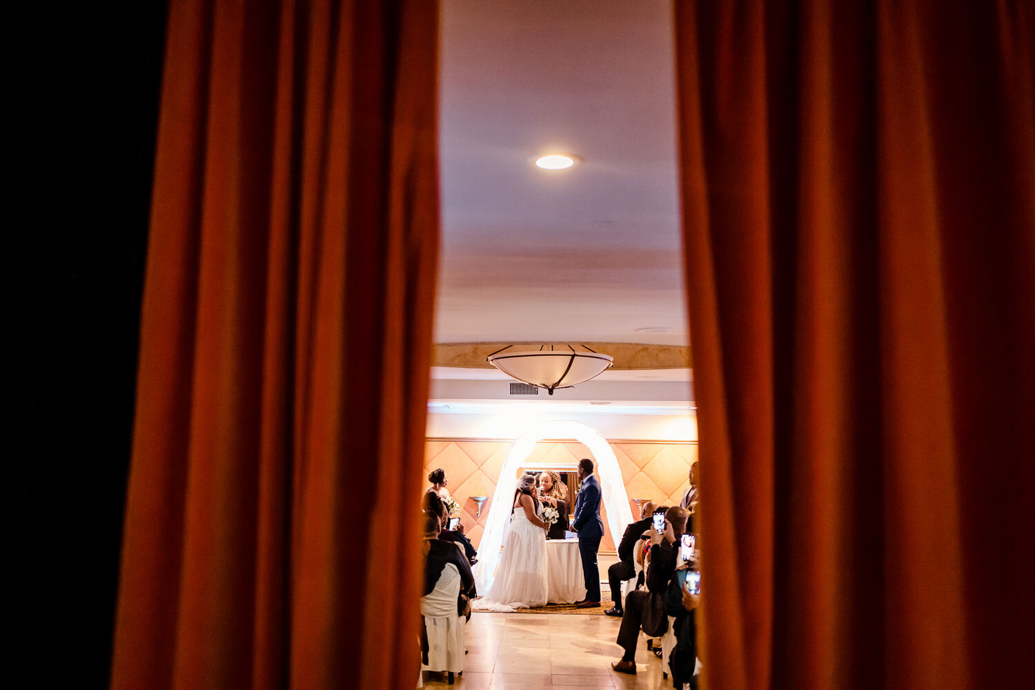 Wedding ceremony through red curtains at The Metropolitan Caterers in Glen Cove 