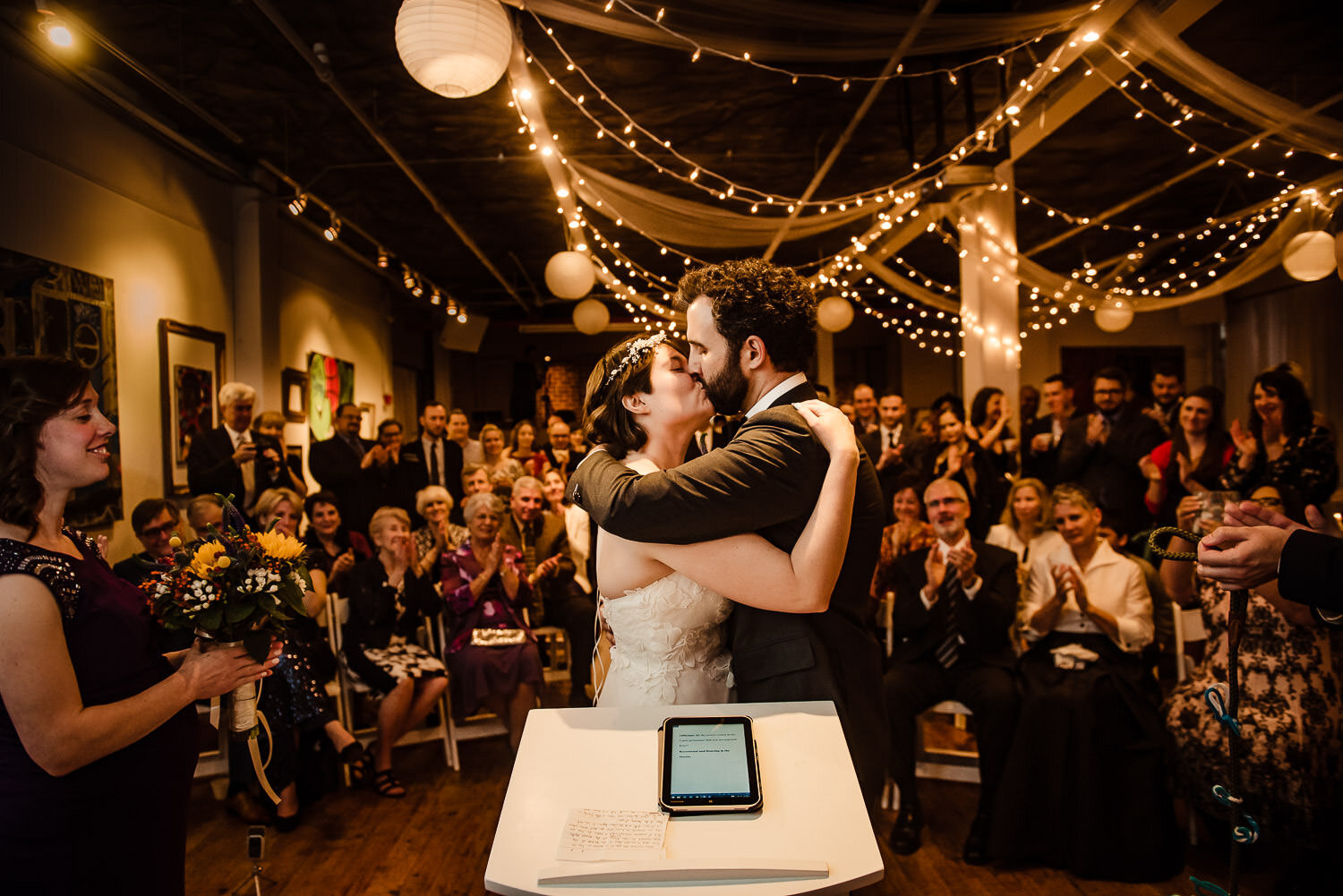 Bride and groom first kiss during ceremony at Aurora Gallery in Long Island City