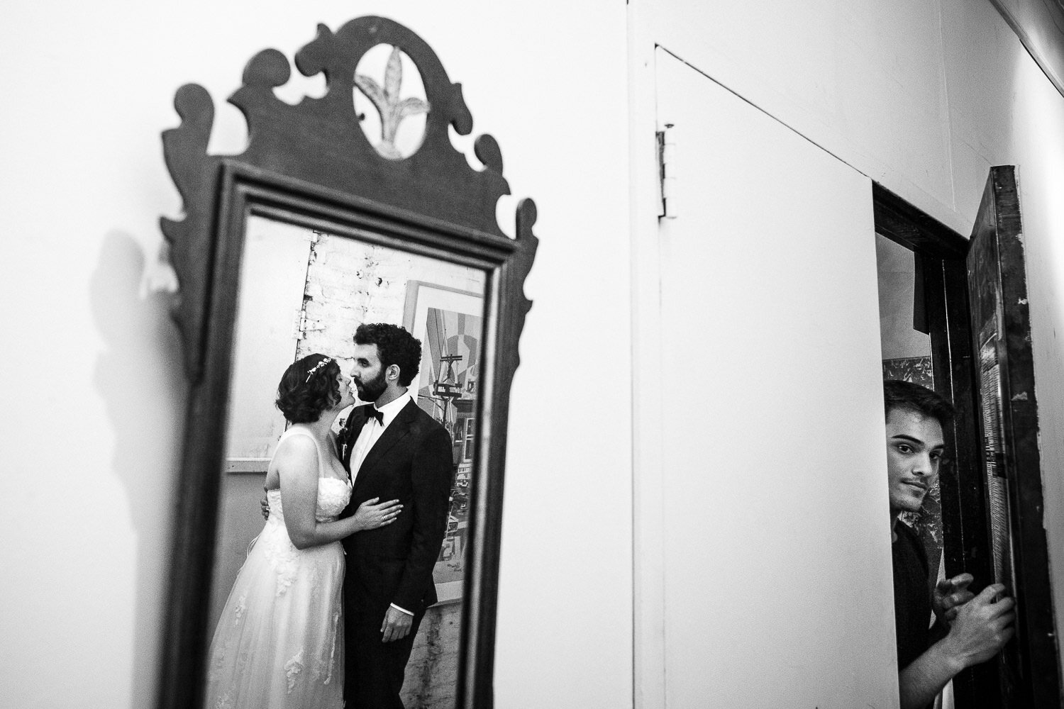 Bride and groom mirror reflection while somebody exits from a door at Aurora Gallery in Long Island City