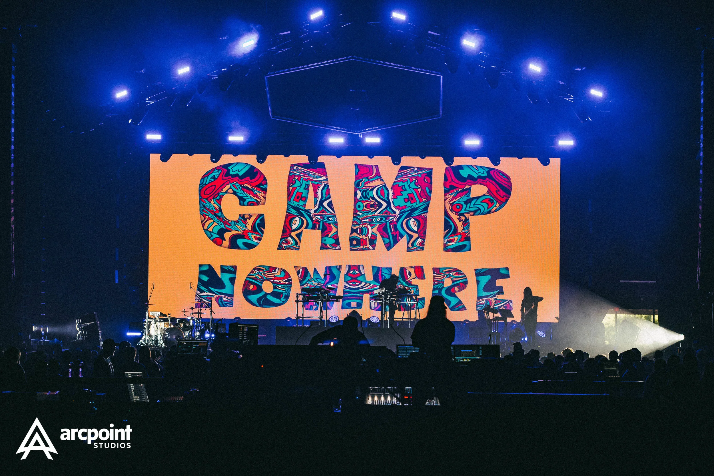 Stage with large screen displaying the colorful message 'GRIP NORTH' during a concert or event, with silhouettes of people and musical instruments in foreground, and lighting illuminating the stage.