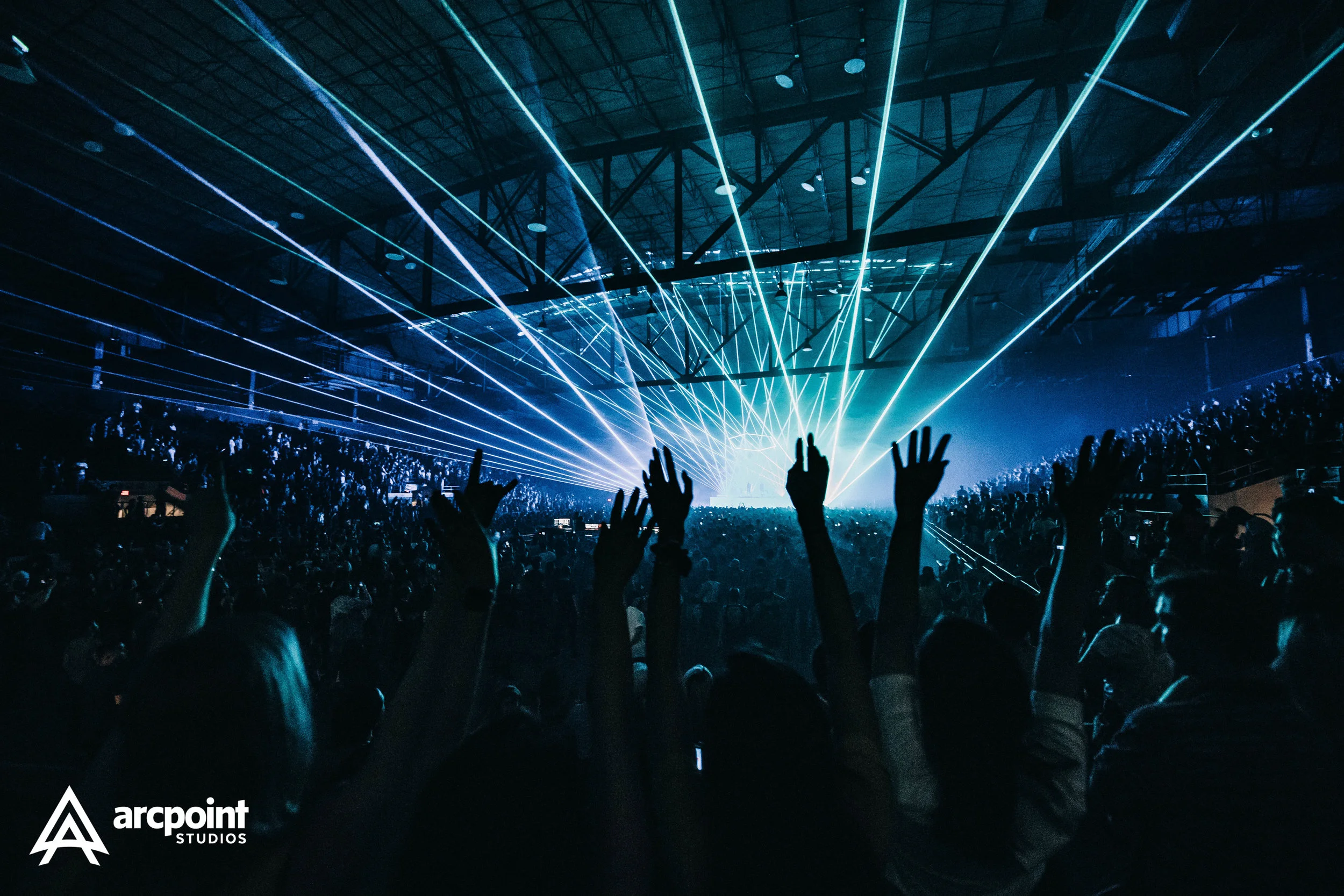 Crowd at a concert or music event with laser light show in a large indoor venue.