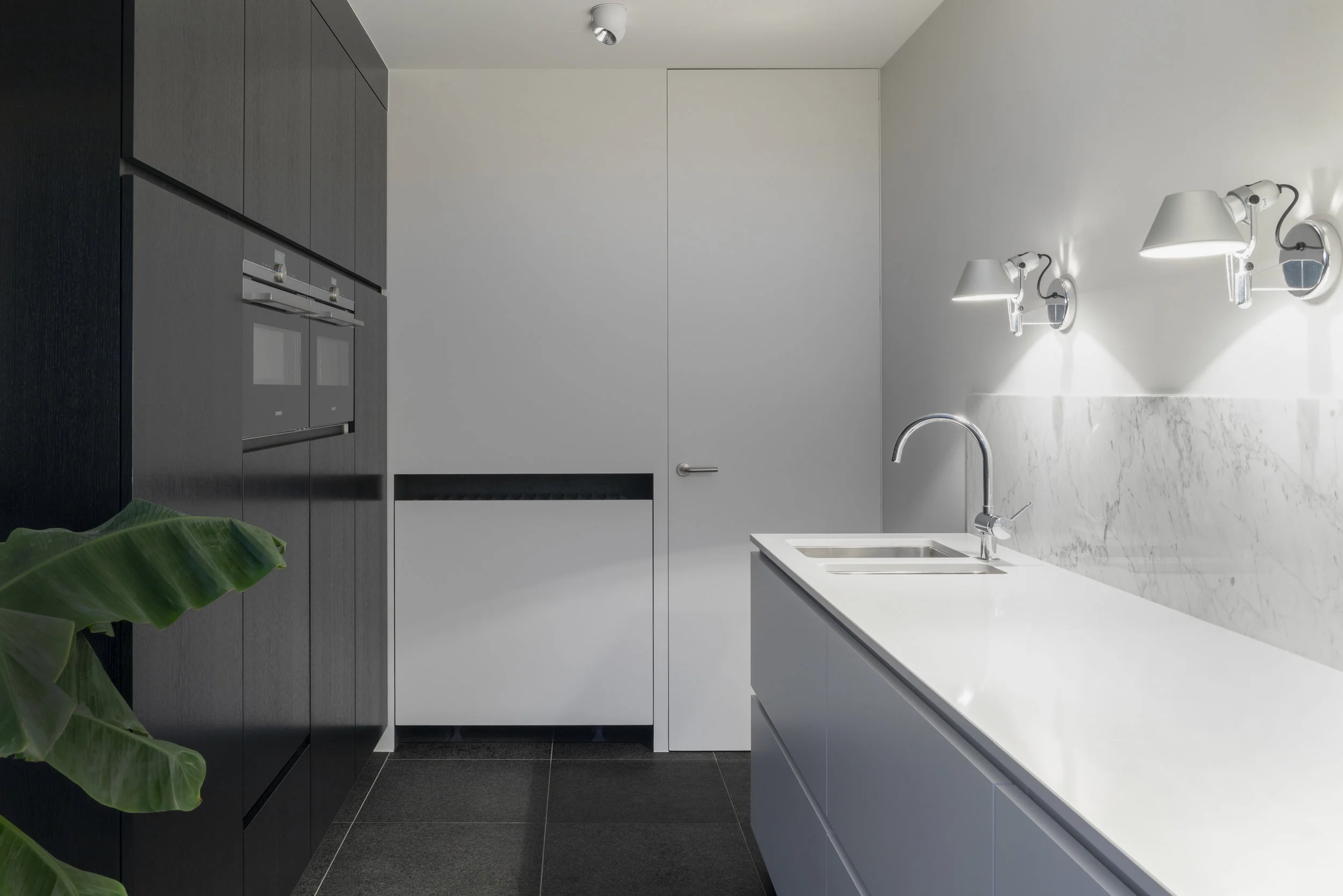 A simple WHITE KITCHEN DESIGN IS ELEVATED THROUGH CONTRAST WITH BLACK APPLiaNCES AND DARK CABINETS.