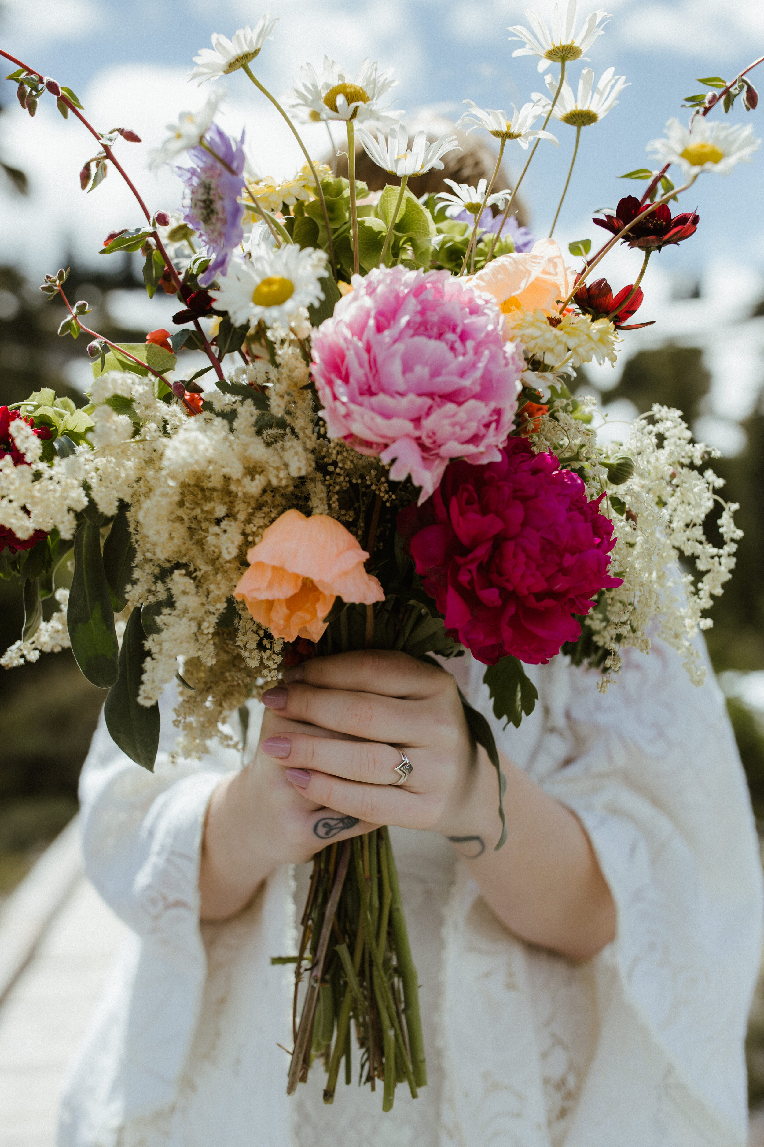 A bridal bouquet of wildflowers and her wedding rings at a mountain elopement at Mt. Baker