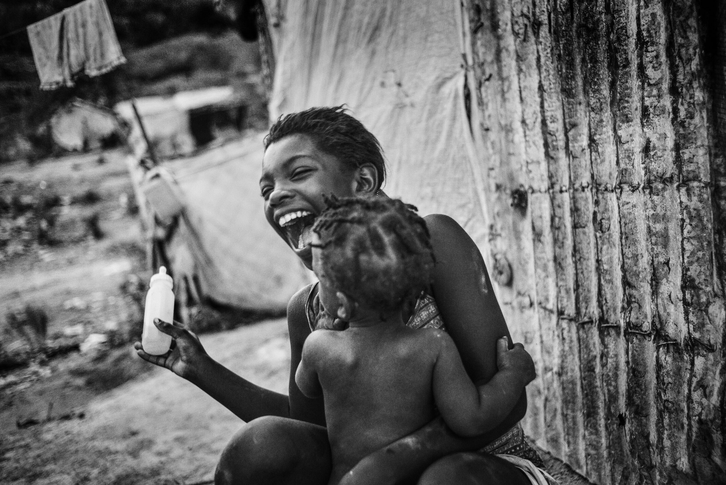  Photo of young girl laughing and playing with a baby 