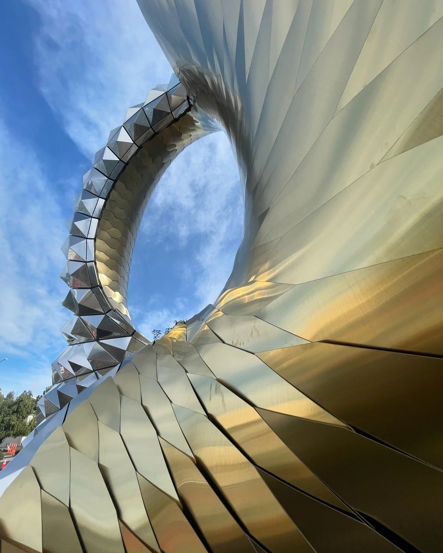 Golden shingles being installed one by one by the team. We love all of the caustic effects and reflections of the site and sky. #shinglestyle #materialism It is always exciting to see the sculpture take shape in person, with many unexpected light and