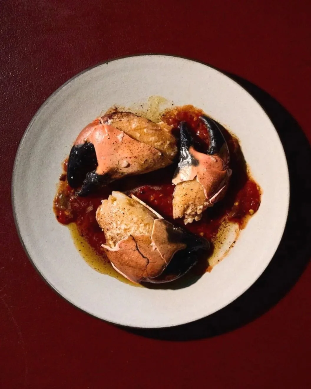 Broken eggs with runny yolks, cooked in a tomato-based sauce on a white plate.
