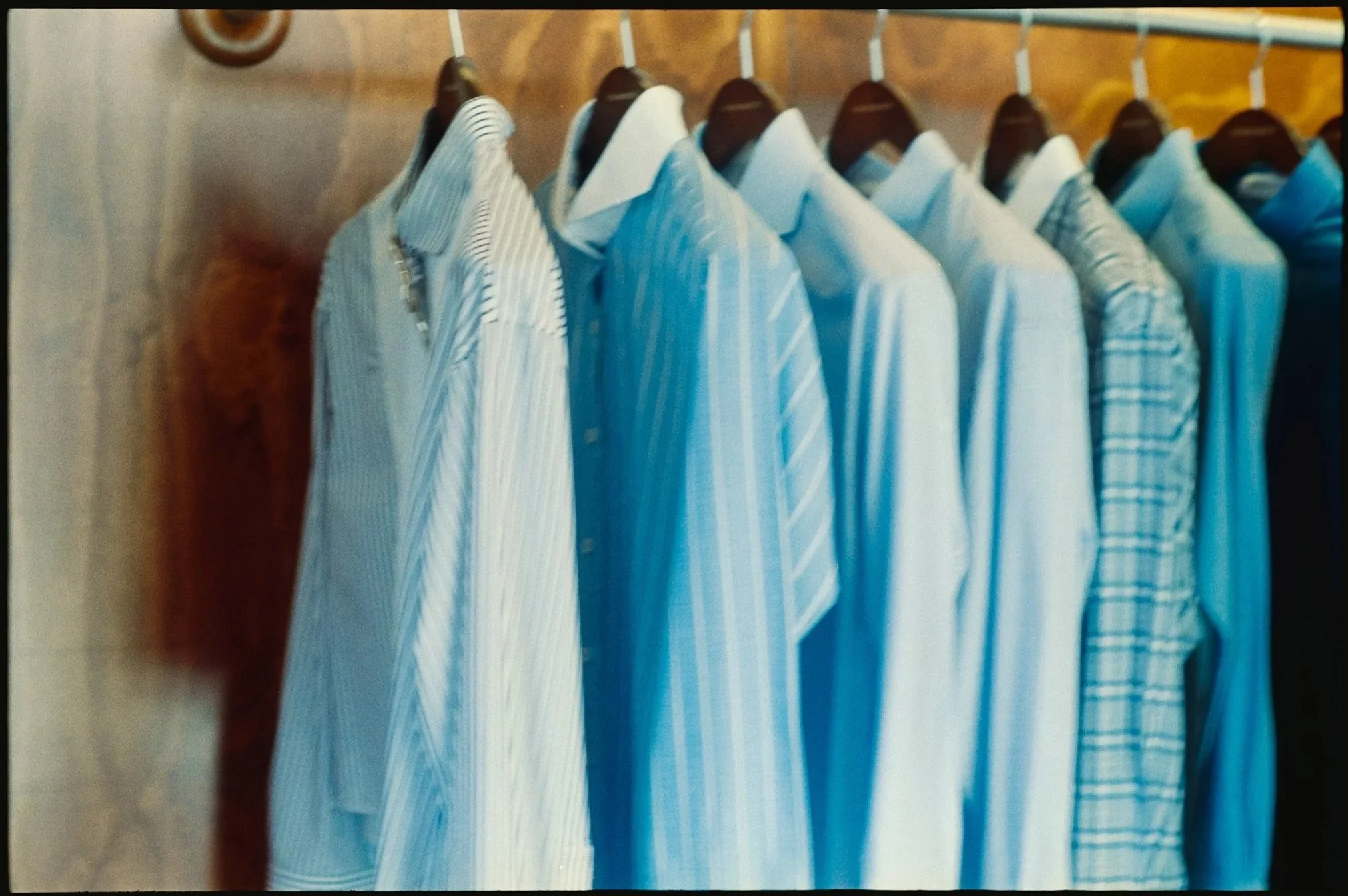 Close-up of a clothes rack with multiple white and light blue striped shirts hanging on black hangers.