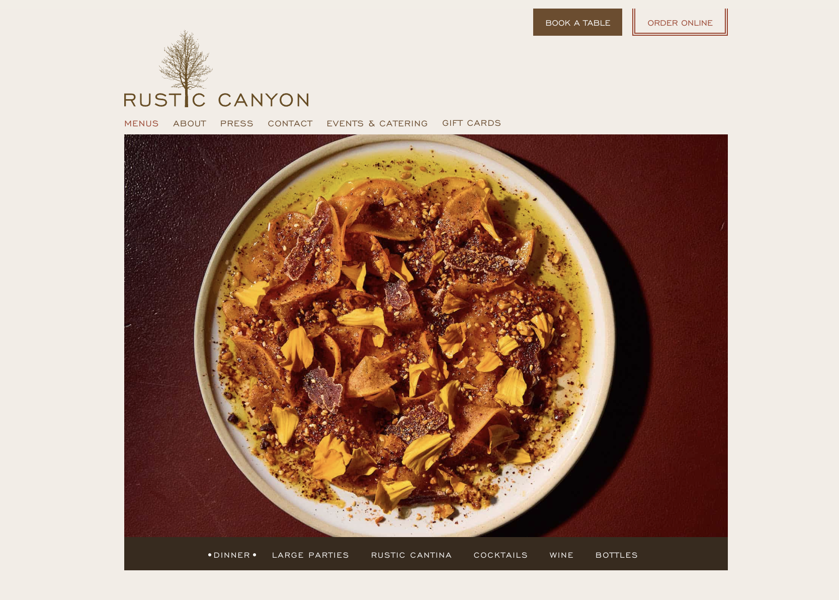 A white bowl of food with shredded meat, yellow flower petals, spices, and oil, on a dark red surface.