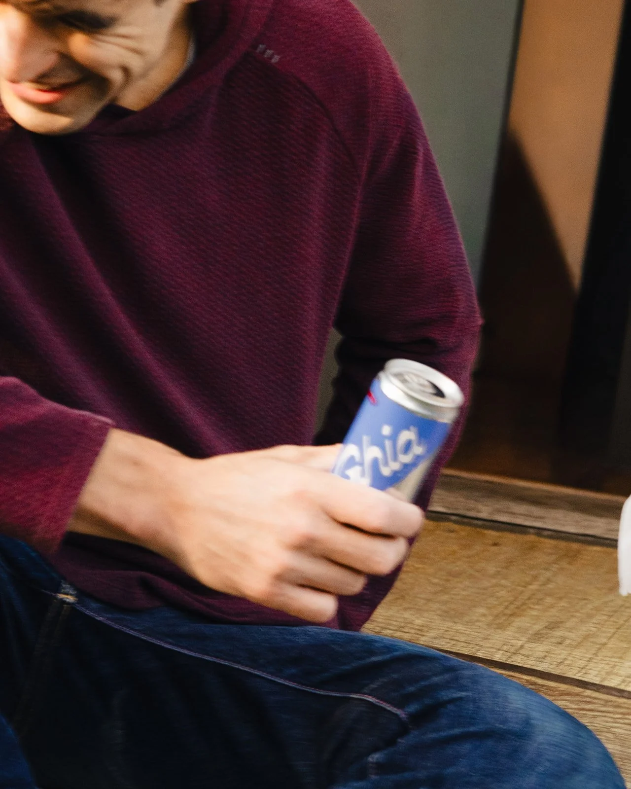 Person in a maroon sweater holding a can of Arizona Chilled Lemonade.