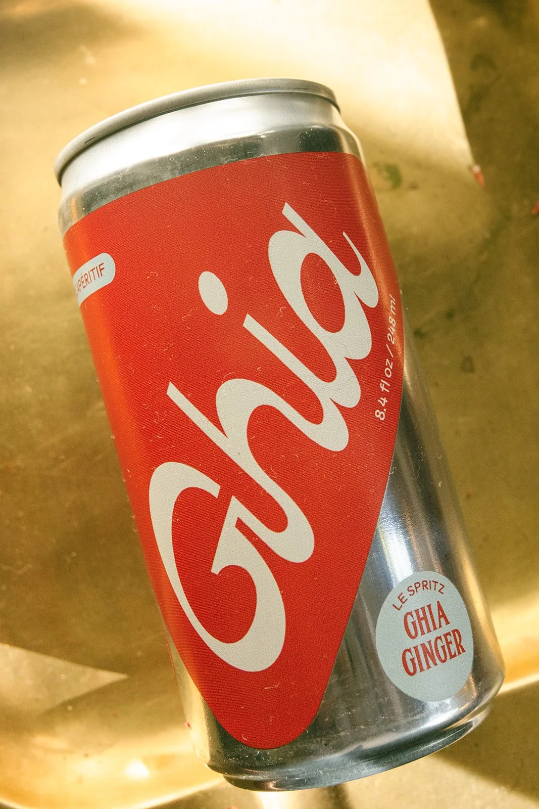 Coca-Cola aluminum can with ginger flavor on a yellow surface.