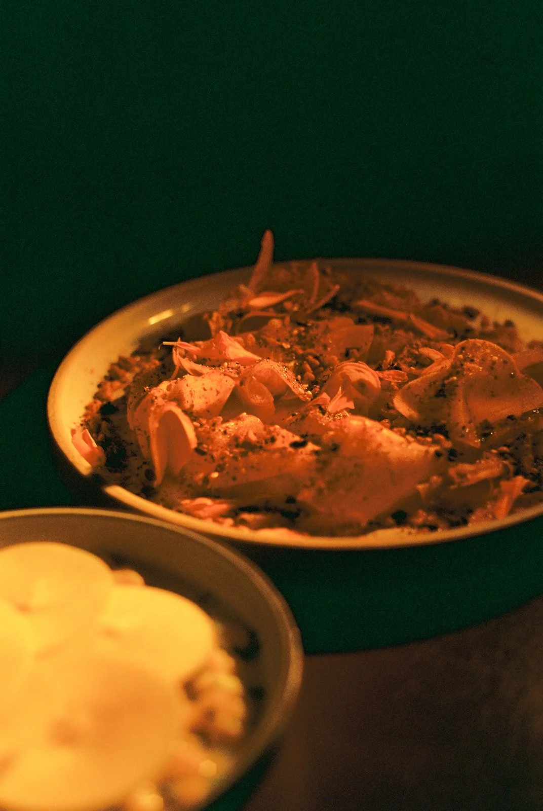 A bowl of shredded cooked chicken with seasonings. In the foreground, a smaller bowl of popcorn.