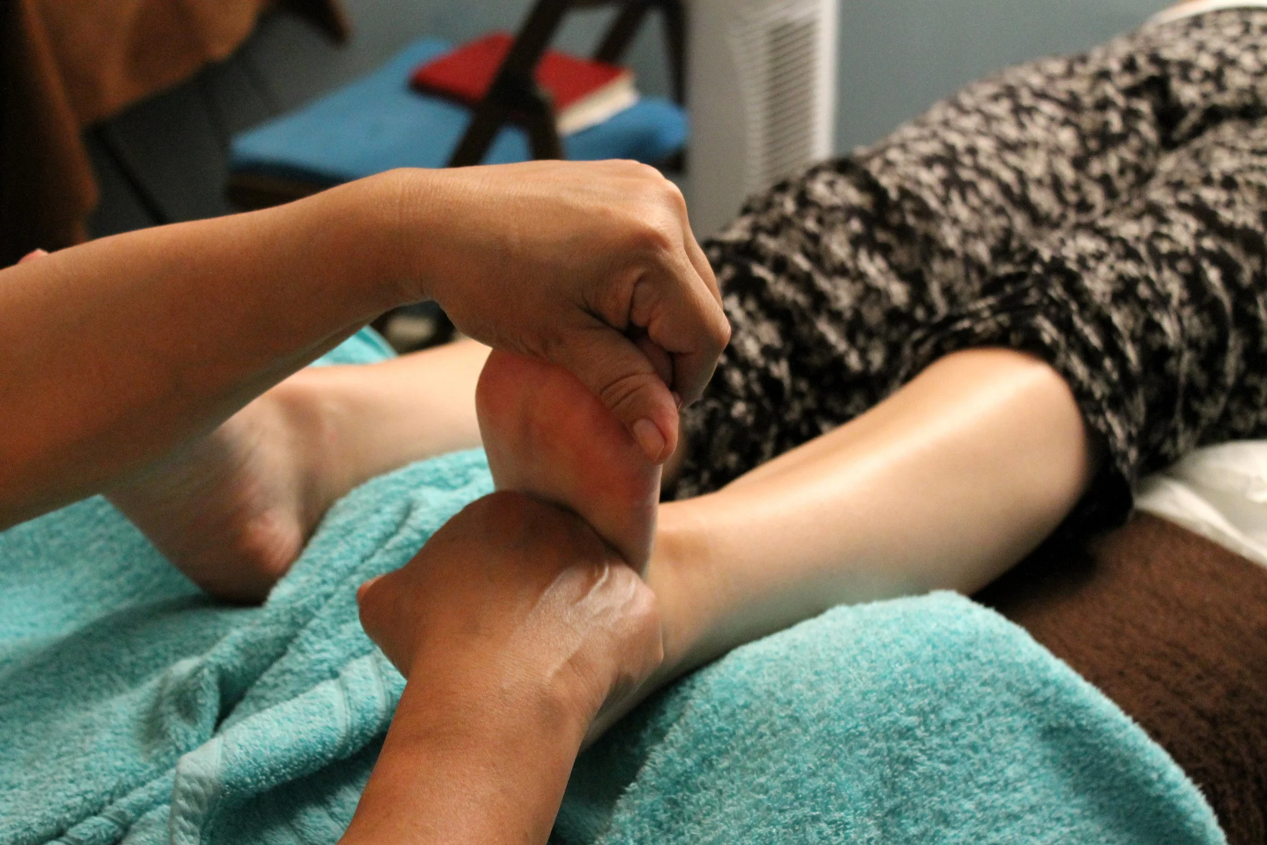 Foot massage being given, person lying down, covered with towel.