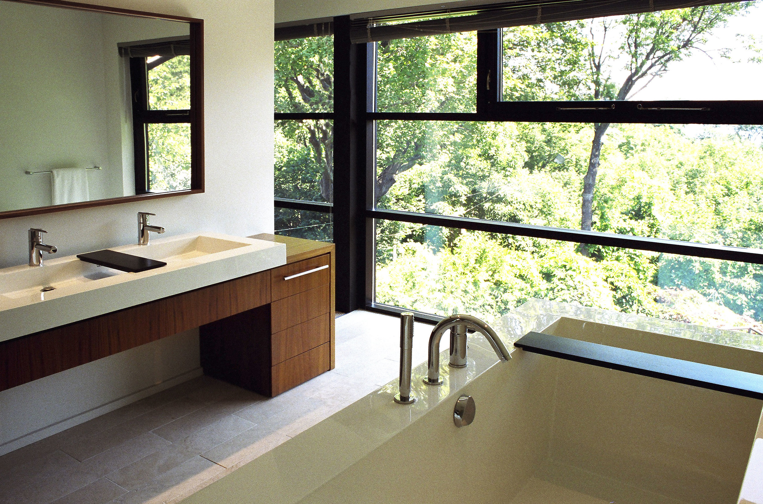 Custom walnut mirror and vanity with Wetstyle Cube double-wide sink. Cube bathtub also by Wetstyle.