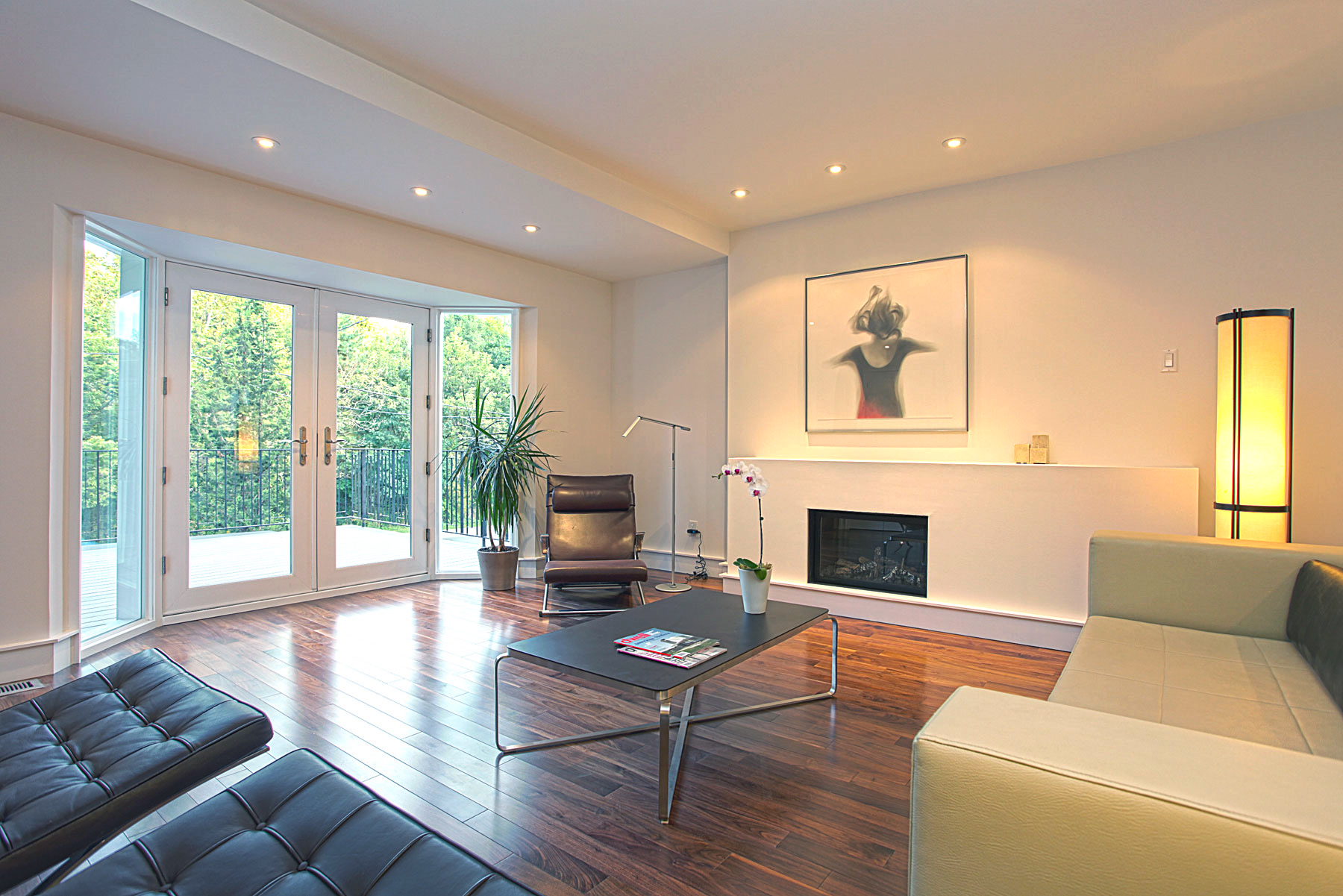 A linear gas fireplace grounds the seating arrangement and provides a focal point. Double doors open to a front terrace that overlooks High Park.