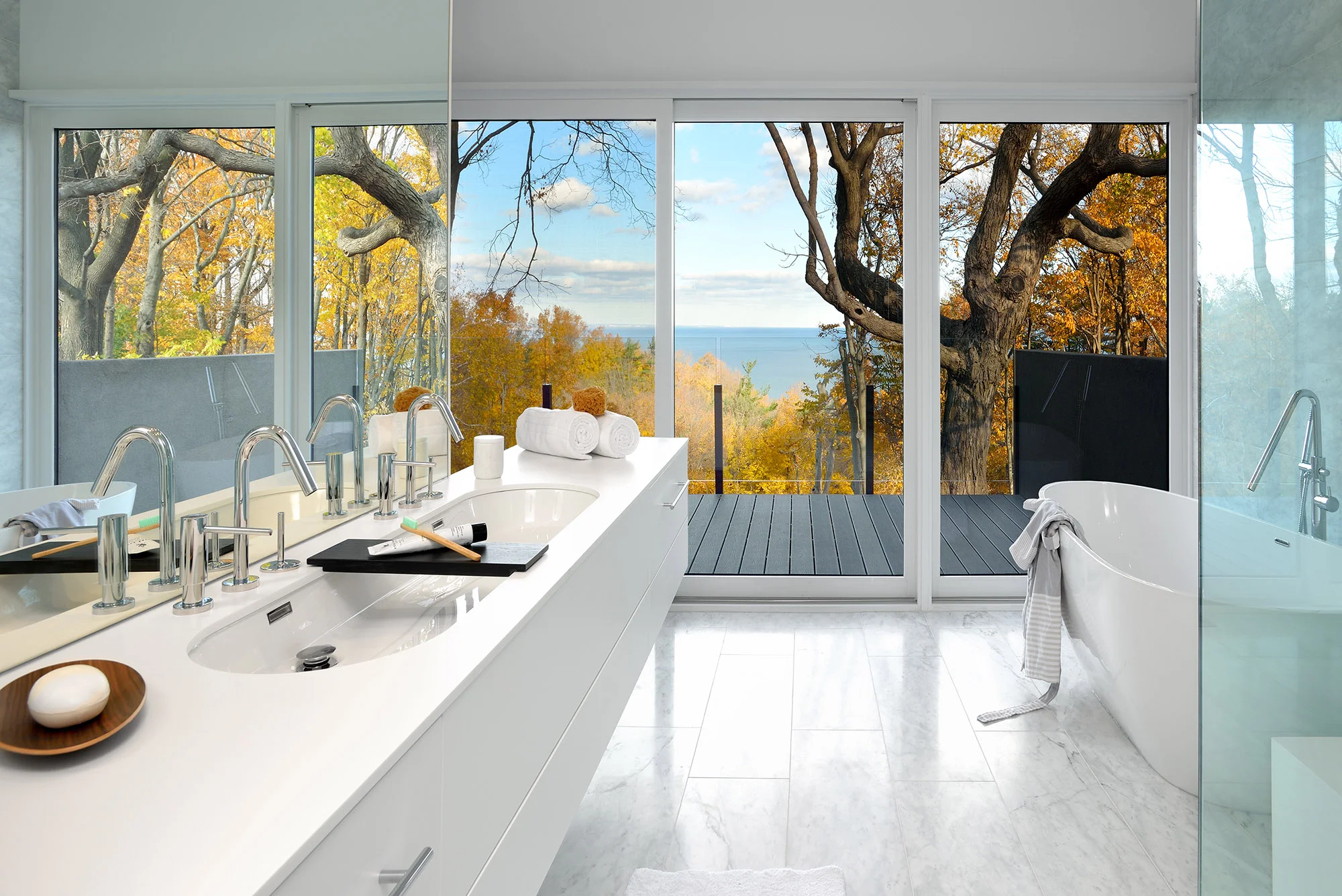 The Master bathroom enjoys heated marble-clad floors. The vanity, featuring a recessed double Ove sink by Wetsyle is clad in Corian on all sides, visually appears as a floating block. The bathtub, shower and toilet (tucked behind the vanity wall) all enjoy a lake view