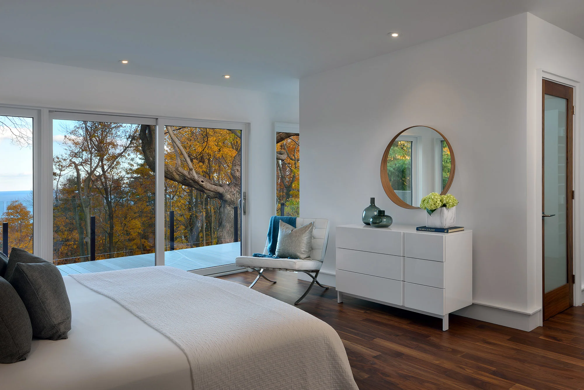 The master bedroom and private terrace have a view over the forest to Lake Ontario. An open entryway to the ensuite is along the glass wall.