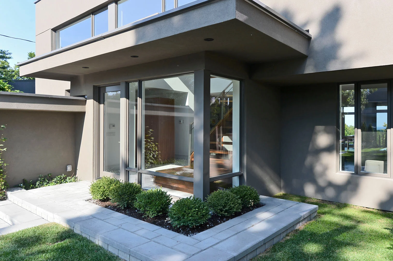 A glass addition to the entryway physically and visually expands the foyer, providing extra space for the custom staircase.