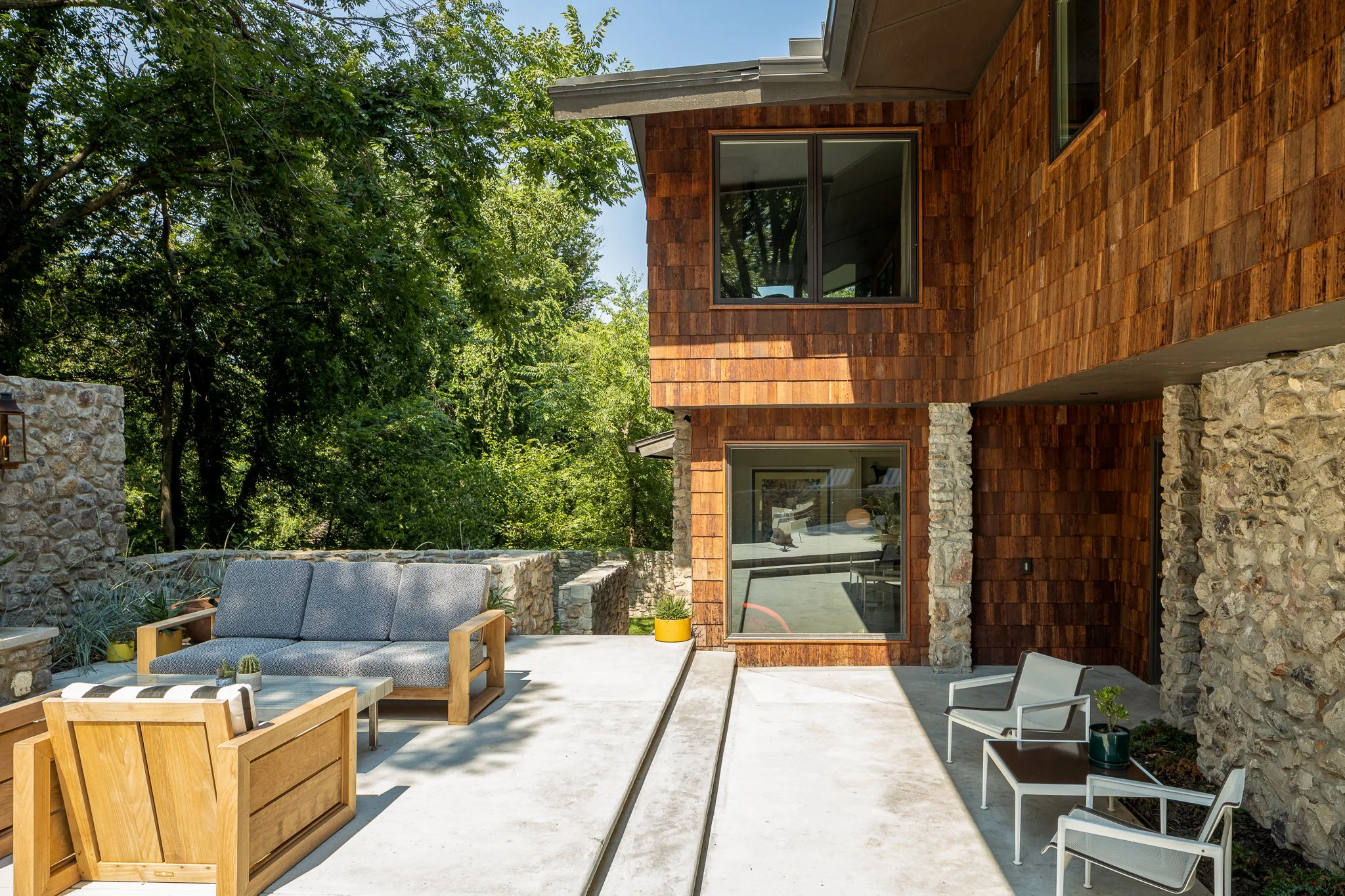 Demolished stone walls were carefully salvaged to repair walls to be retained and create new stone features. The hardscape design simply follows established circulation paths while better organizing a set of outdoor living areas. A new fireplace giv