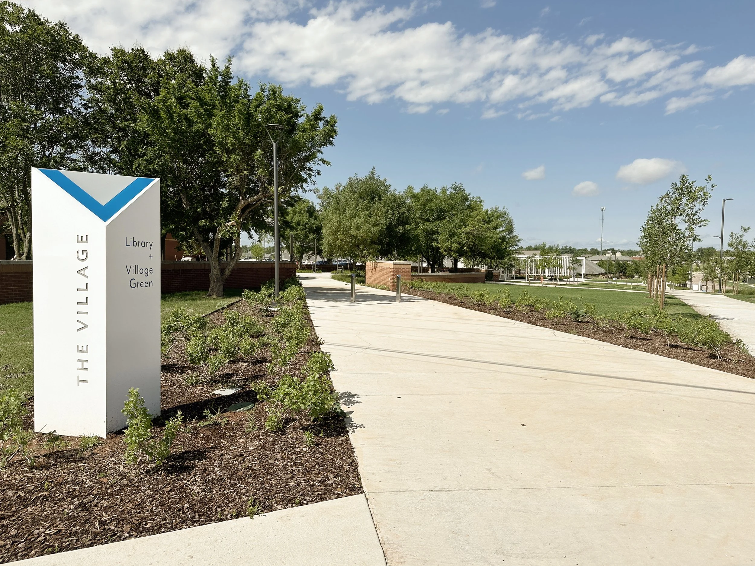  New openings in the brick wall encircling the Village Green establish connections to the linear park. Wayfinding signage reinforces an identity for The Village and its civic amenities. V shaped resin panels light up at night for added interest.  ___